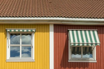 Yellow and red building with windows, green and white striped awnings, and a brown roof.