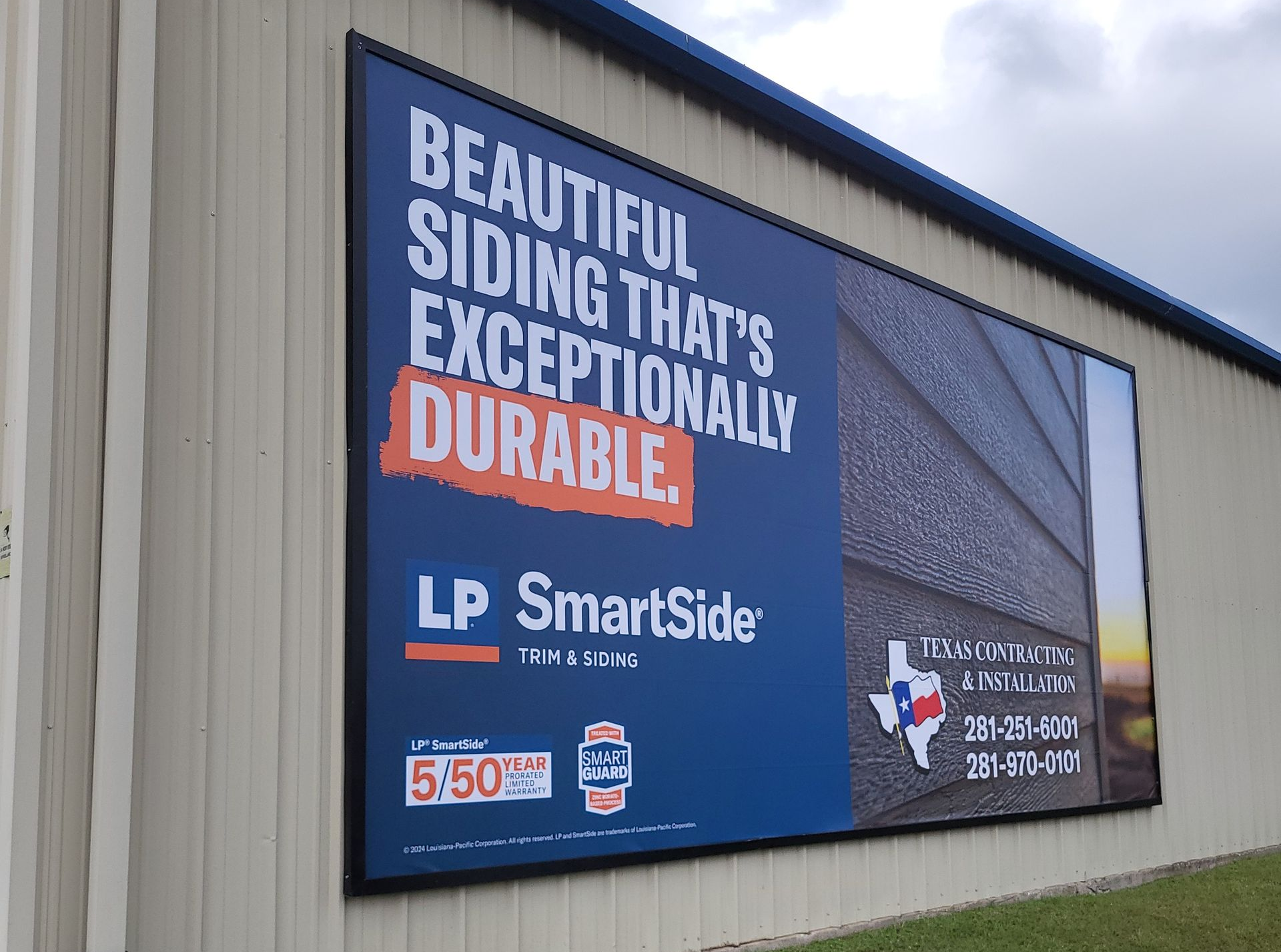 Exterior view of a house with a gray shingled roof and small windows. Green trees are in the background. A house roof with dormer windows against a backdrop of green trees and a blue sky.