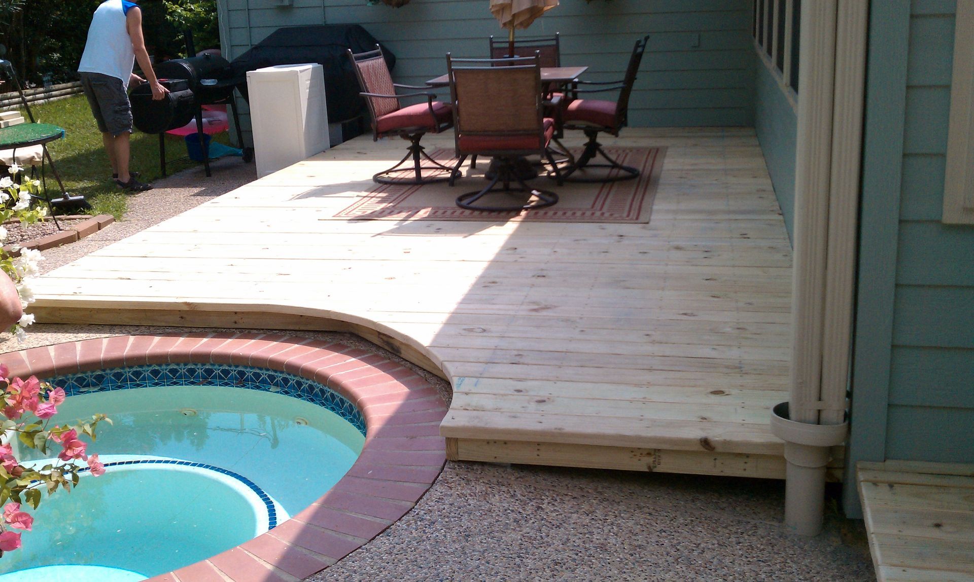 Person using a power drill to screw down composite deck boards. Person using a drill to screw down deck boards; outdoor setting.