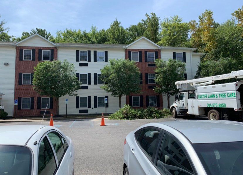 Truck with lift parked in front of large house — Daniels, WV — Mastiff Lawn & Tree Care