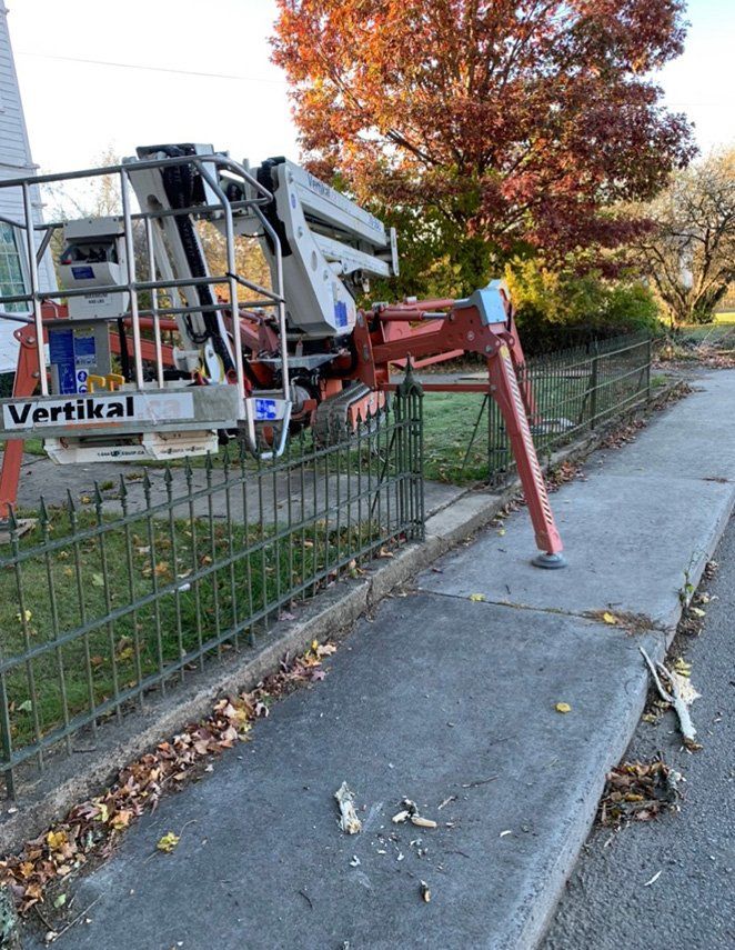 Aerial lift in between metal fence — Daniels, WV — Mastiff Lawn & Tree Care