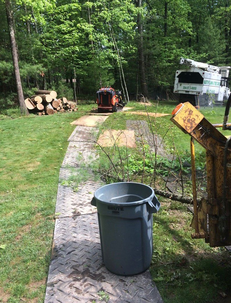 Trash can in front of logs and equipment — Daniels, WV — Mastiff Lawn & Tree Care