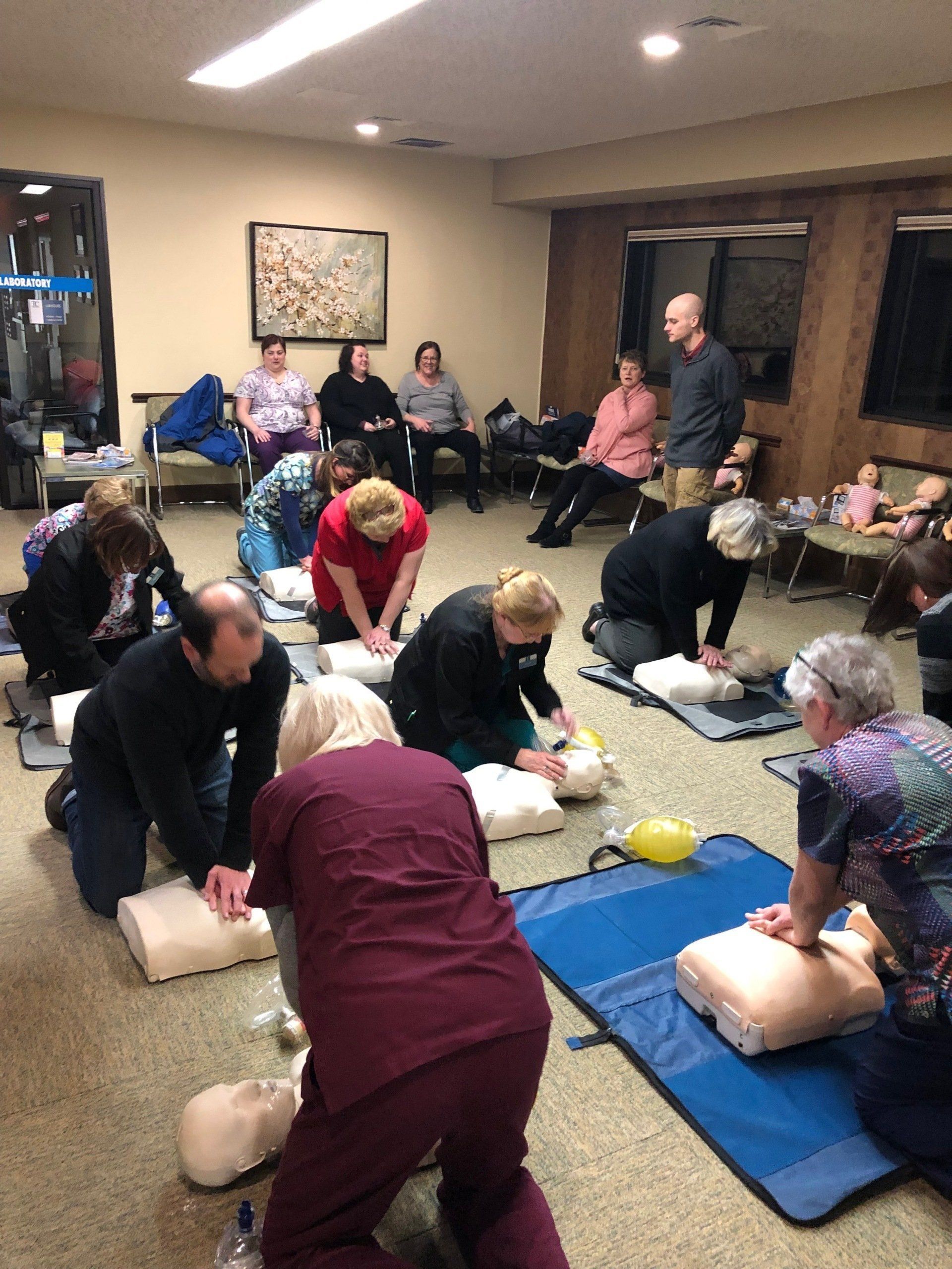 A group of people are practicing first aid in a room.