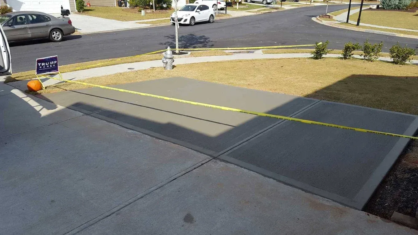 Newly poured concrete driveway with caution tape in residential setting.