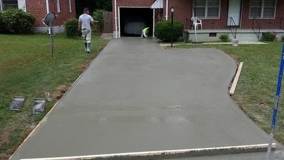 Workers smoothing fresh concrete driveway.