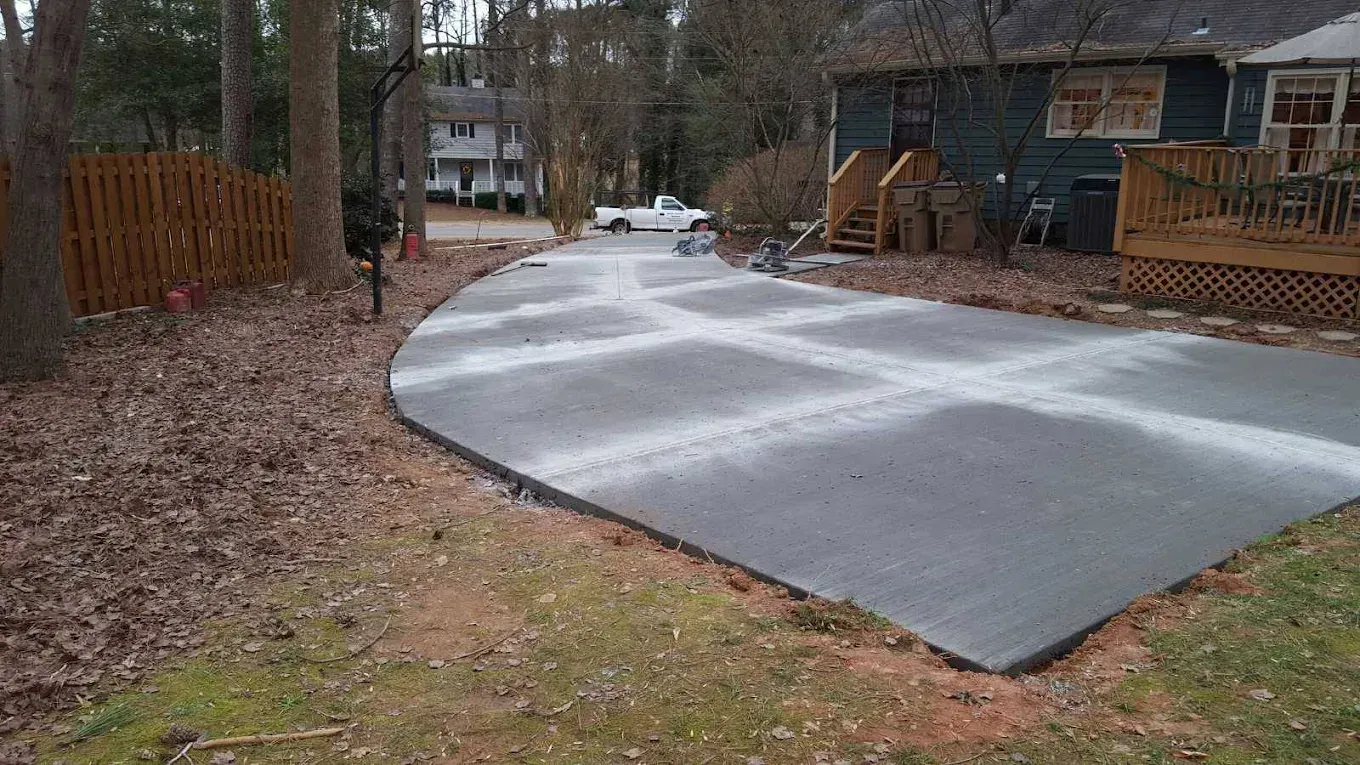 Newly poured concrete driveway with grid pattern; house in background.