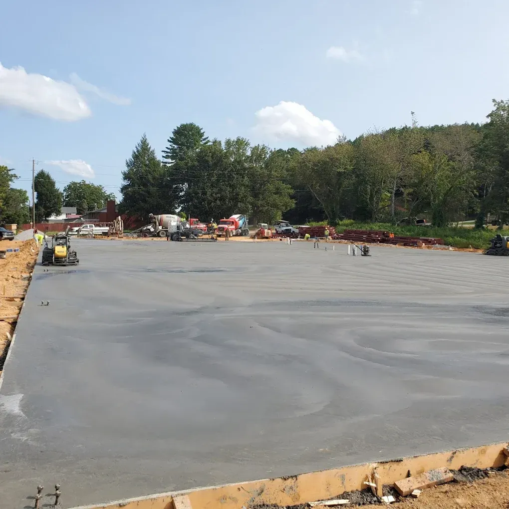 Construction site with a large, freshly poured concrete slab, blue sky.