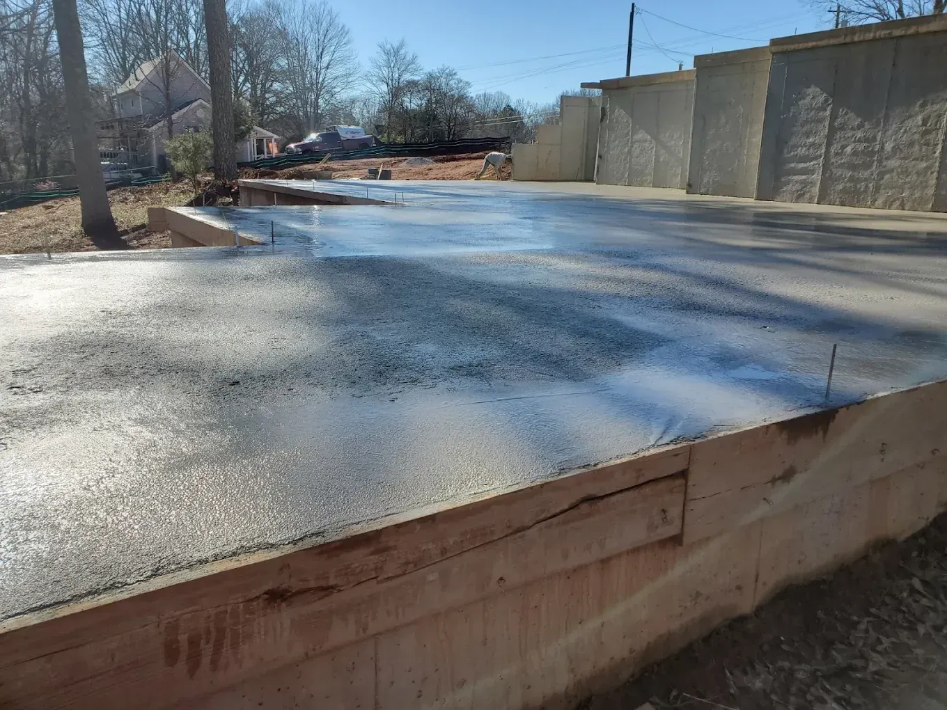 Newly poured concrete slab with wooden formwork, outdoors.