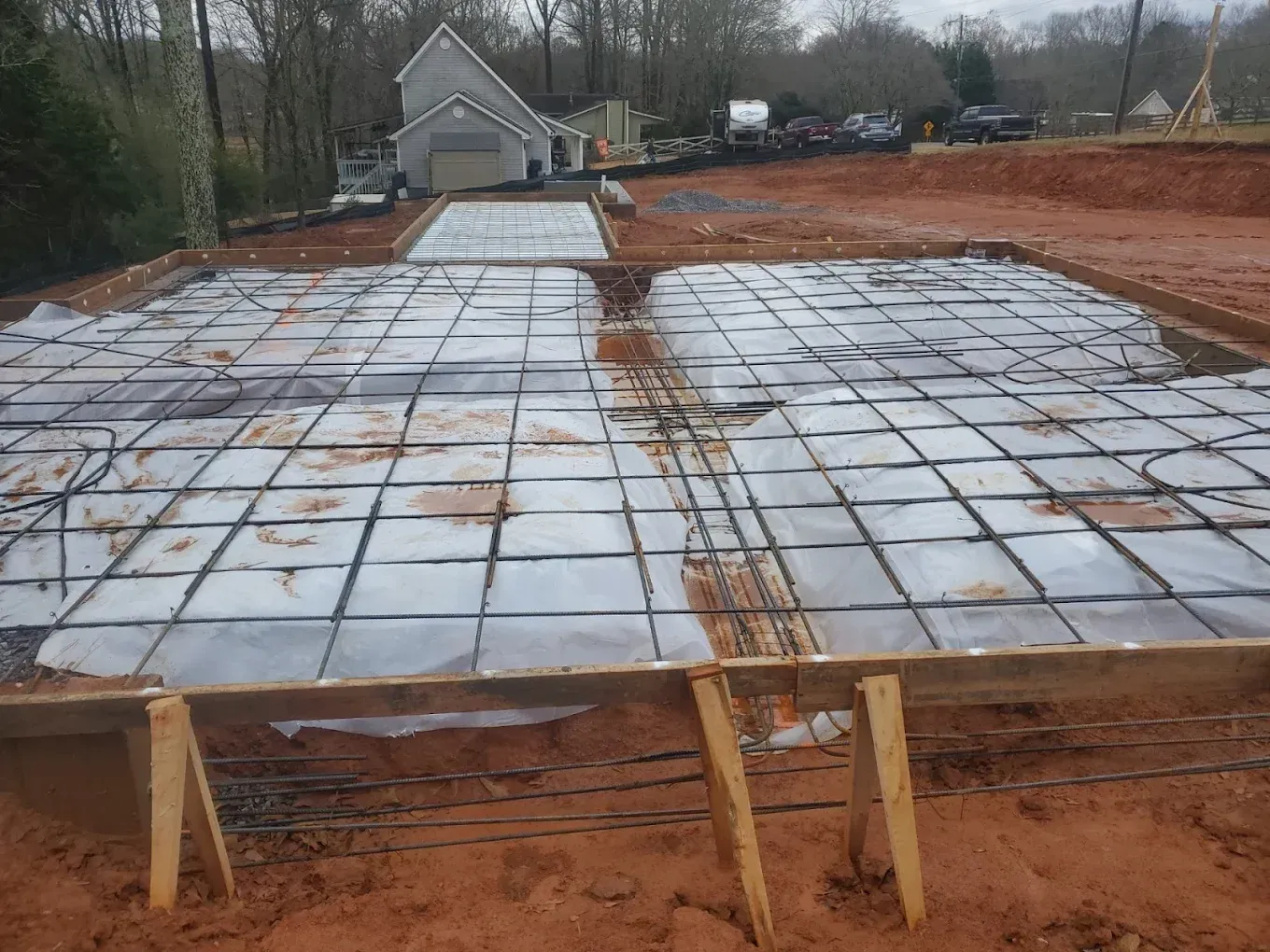 Construction site with a wooden foundation, rebar grid, and tarps, ready for concrete.