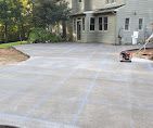 Newly poured concrete driveway next to a light green house.