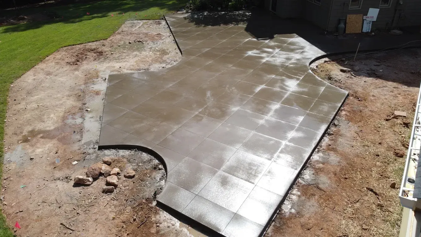 Newly poured concrete patio with a curved edge, in a yard.
