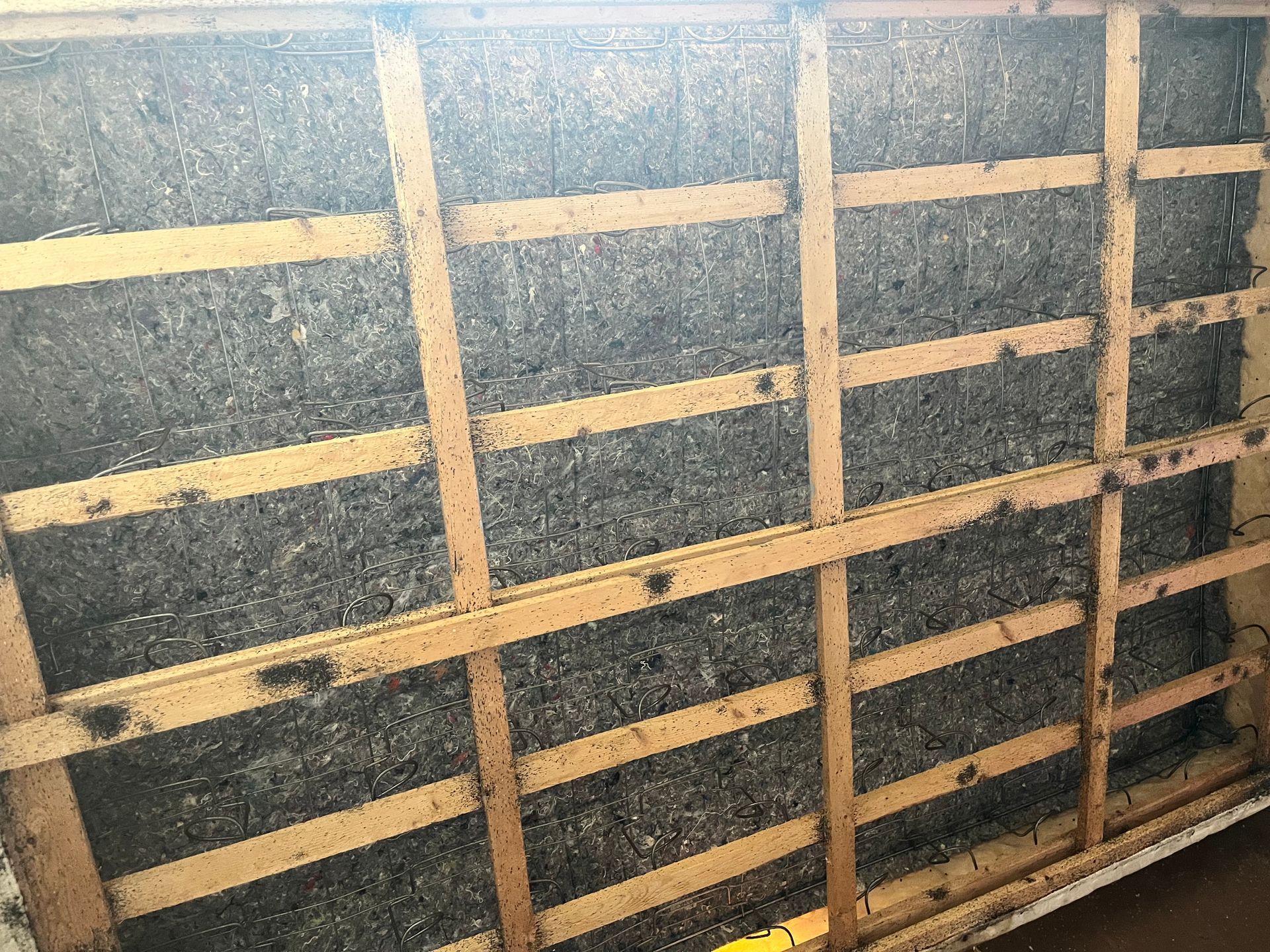 Wooden framework with dark insulation filling the spaces.