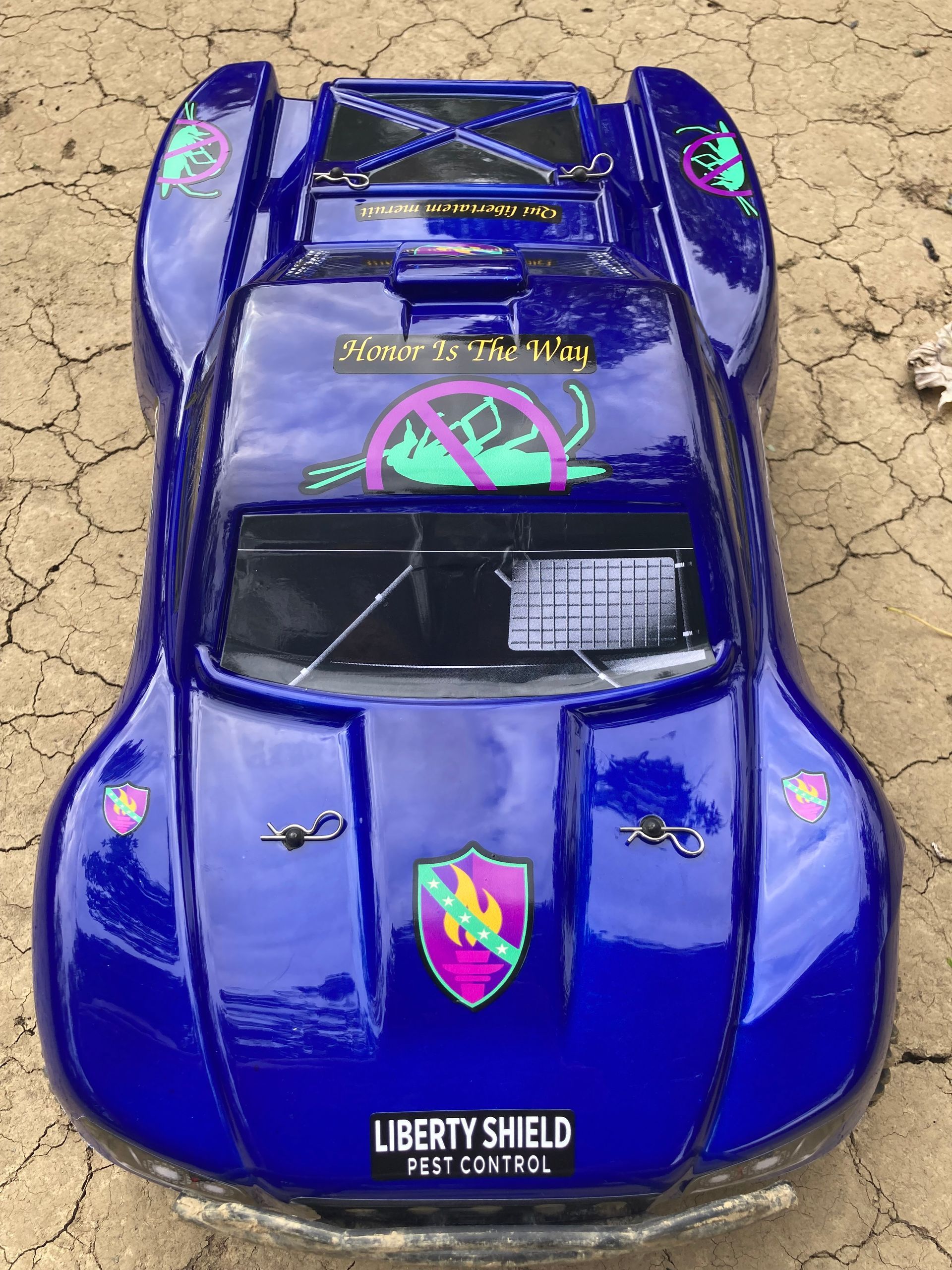 Blue RC car body with Liberty Shield Pest Control branding.