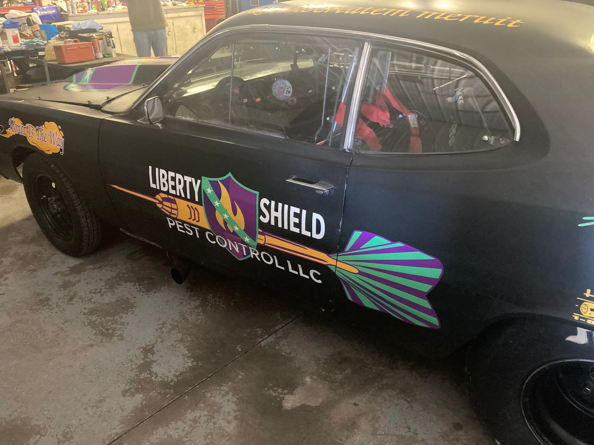 Black race car with Liberty Shield logo and black wheels.