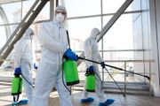 A group of people in protective suits are disinfecting a building.