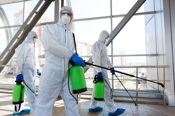 A group of people in protective suits are disinfecting a building.