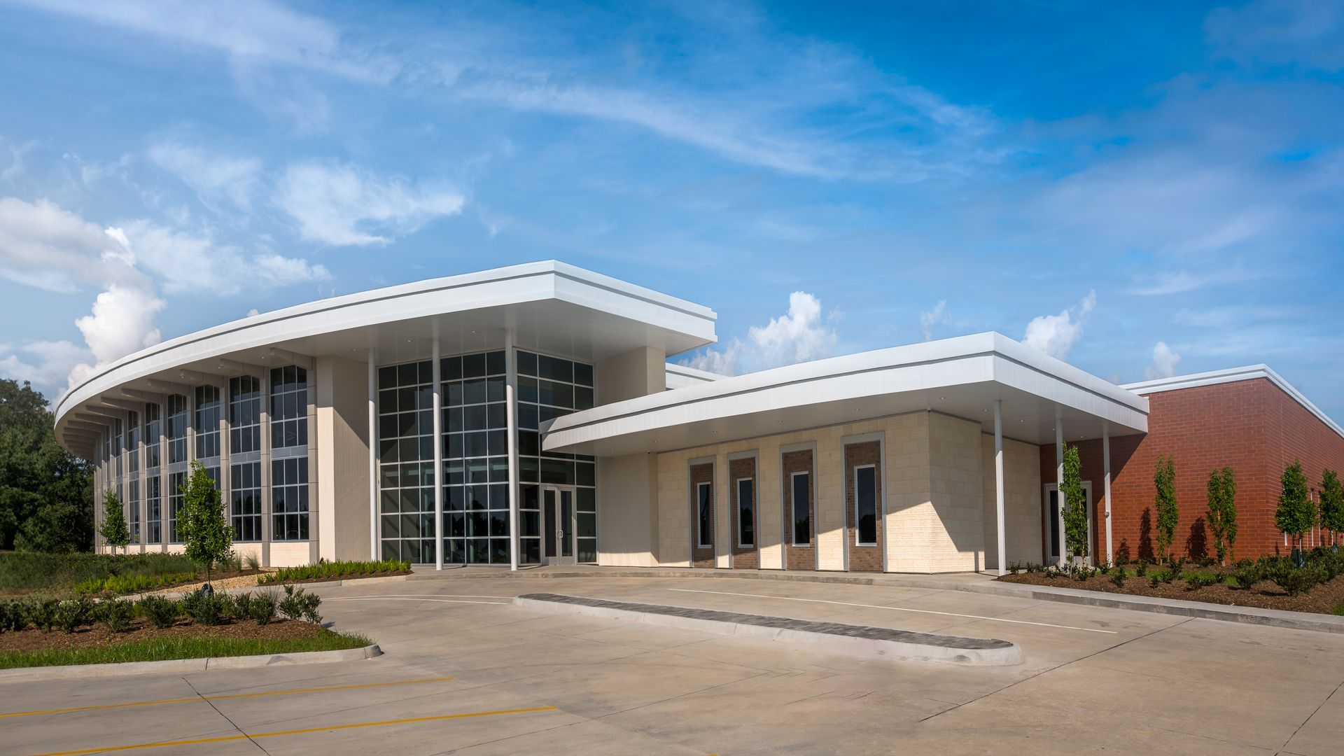 A large building with a lot of windows and a parking lot in front of it.