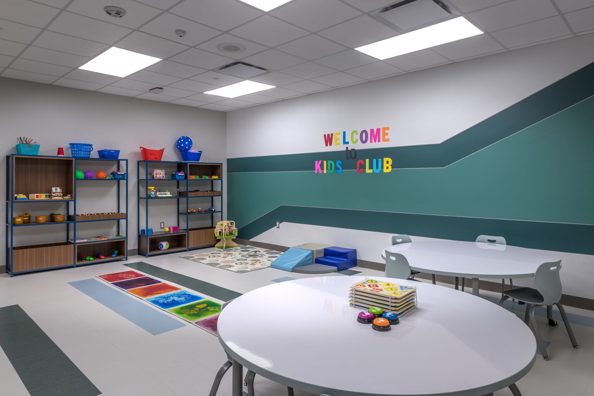 A children 's room with tables and chairs and a welcome sign on the wall.