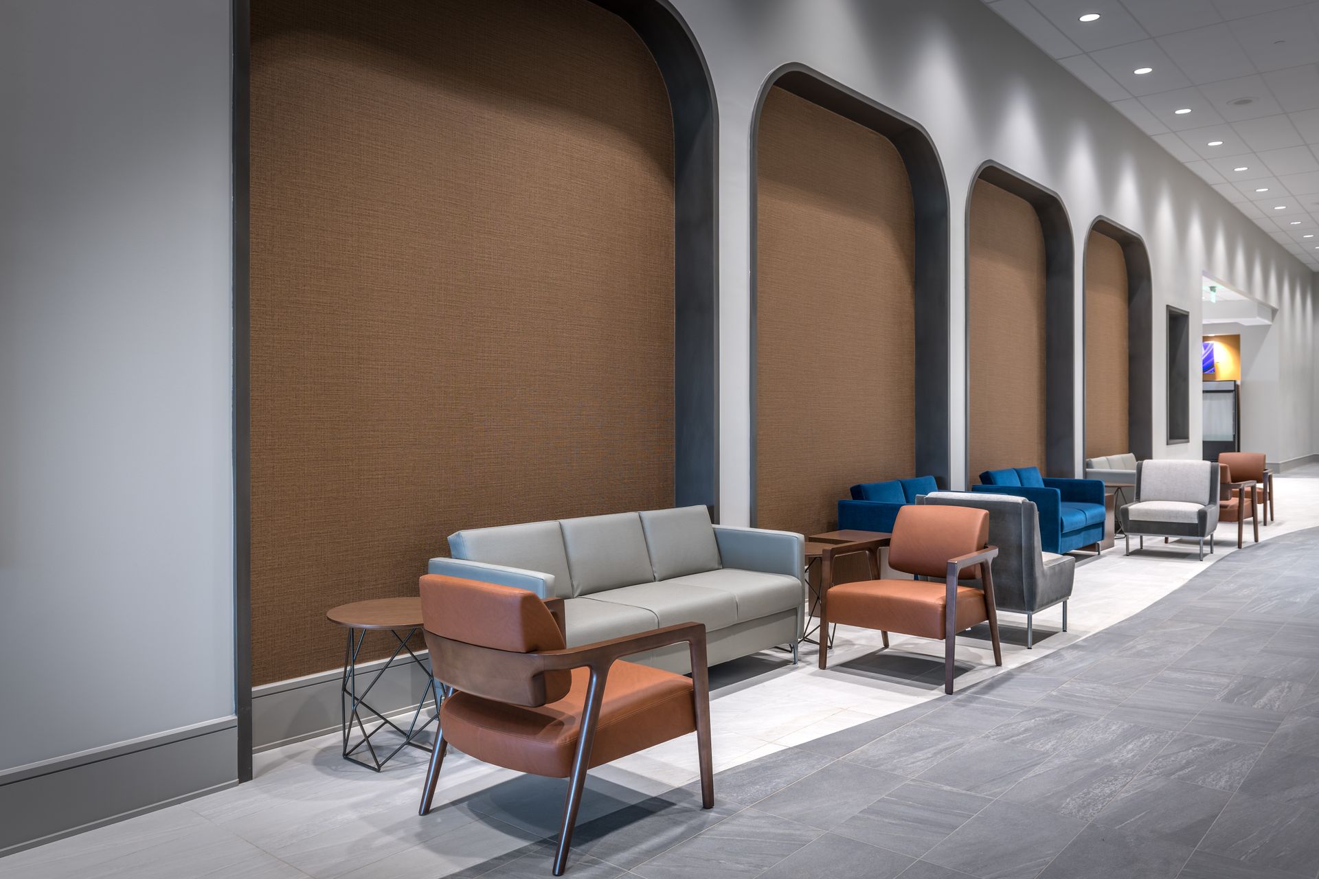 A long hallway with a couch and chairs in it.