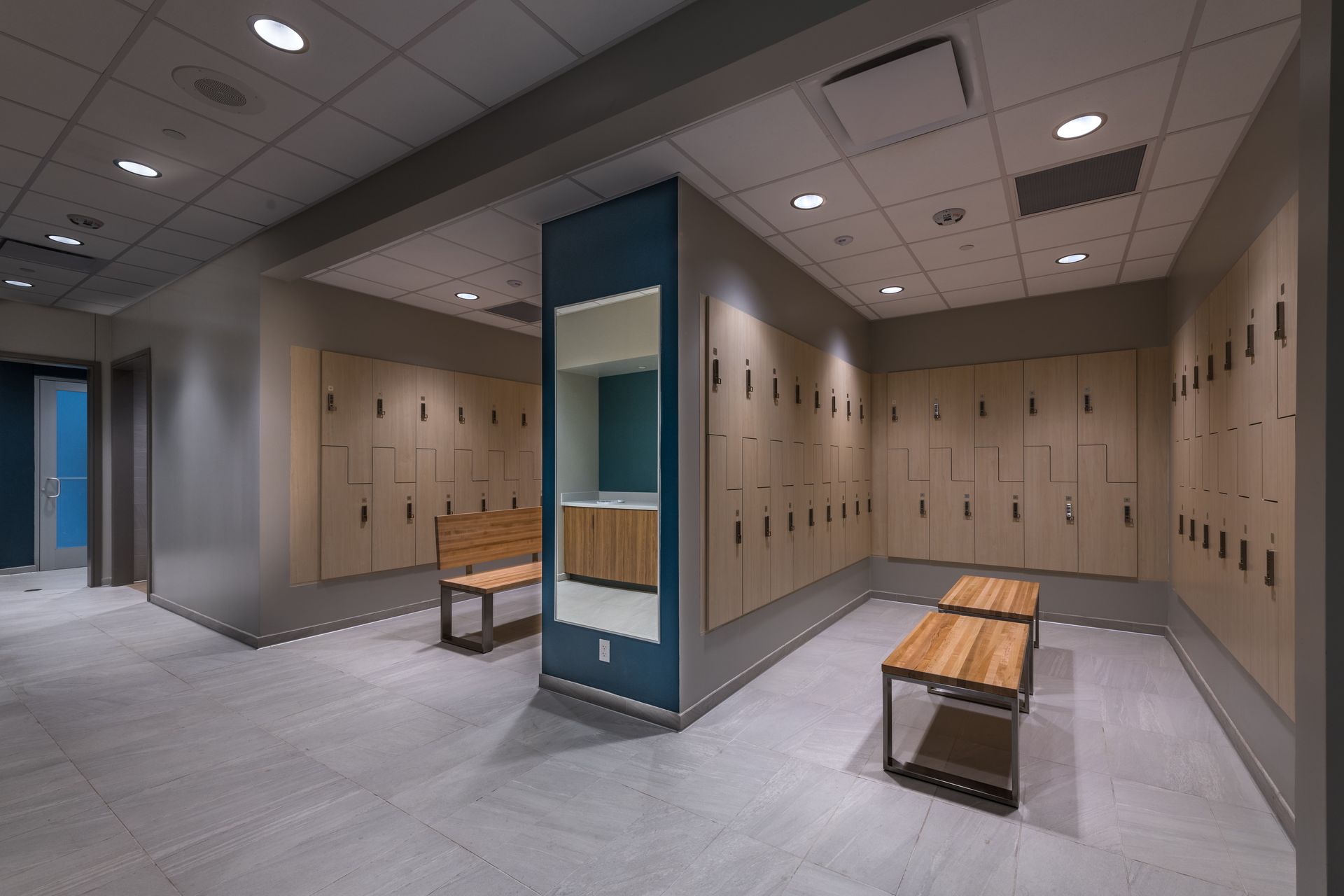 A locker room with lots of lockers and a mirror.