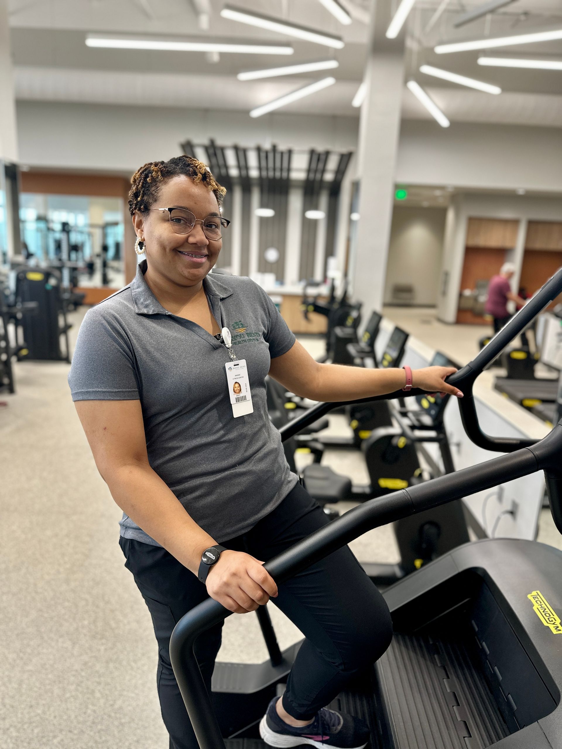 A woman is sitting on a treadmill in a gym.
