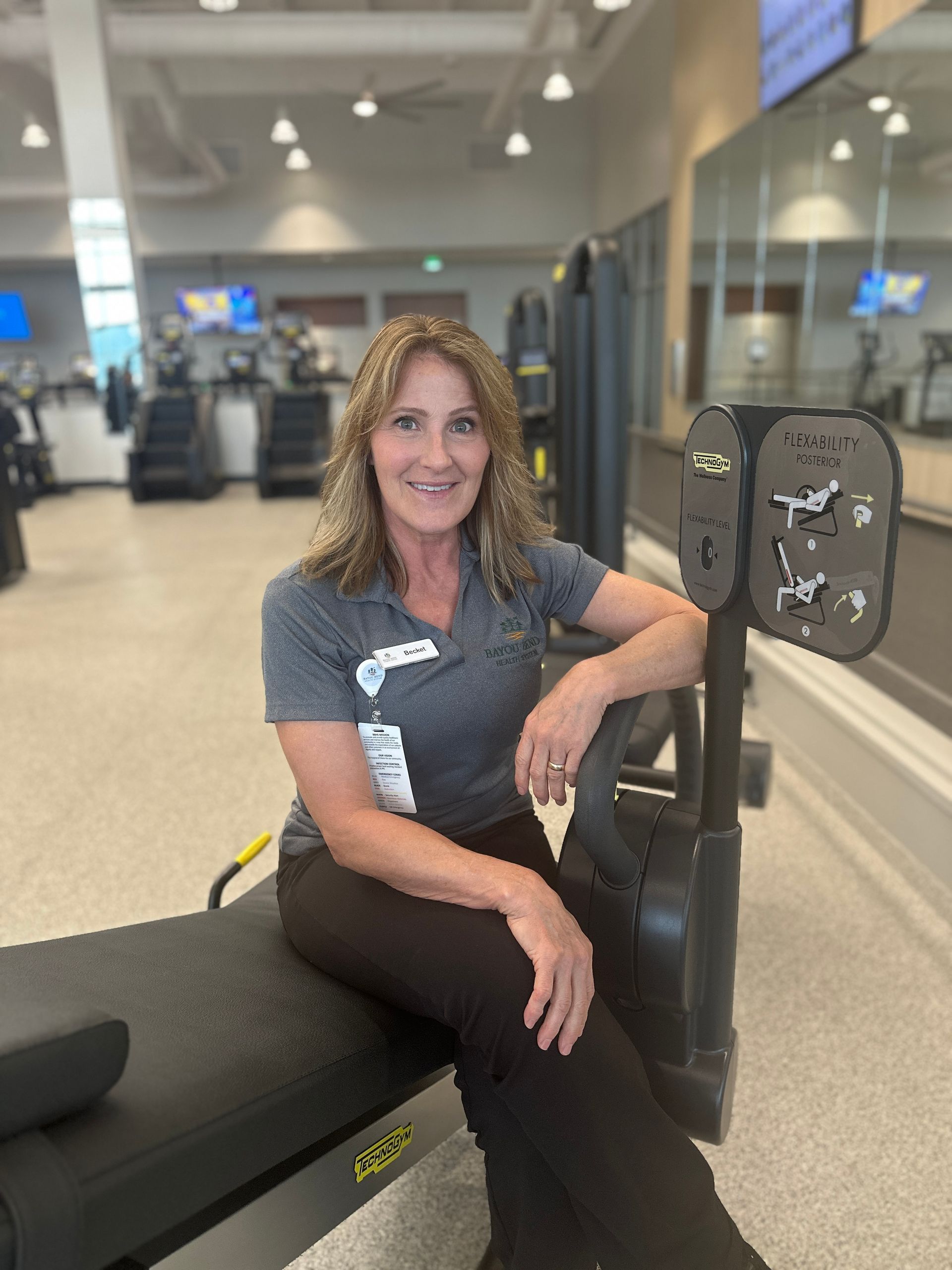 A woman is sitting on a bench in a gym.