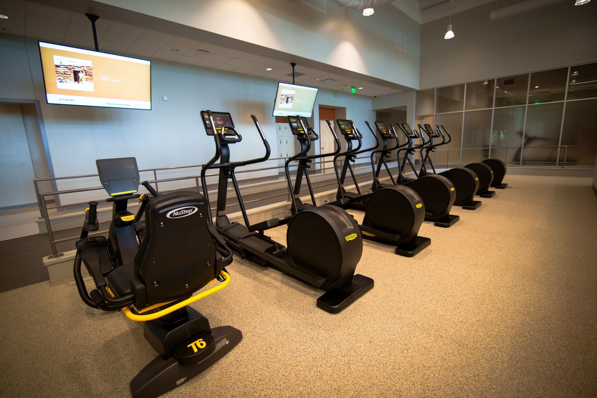 A row of ellipticals are lined up in a gym.