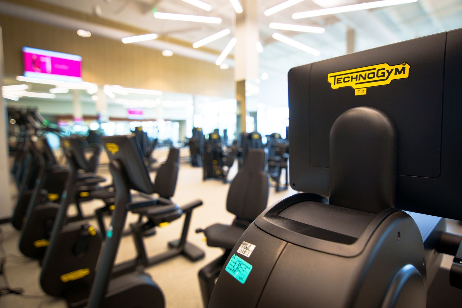 A row of exercise bikes are lined up in a gym.