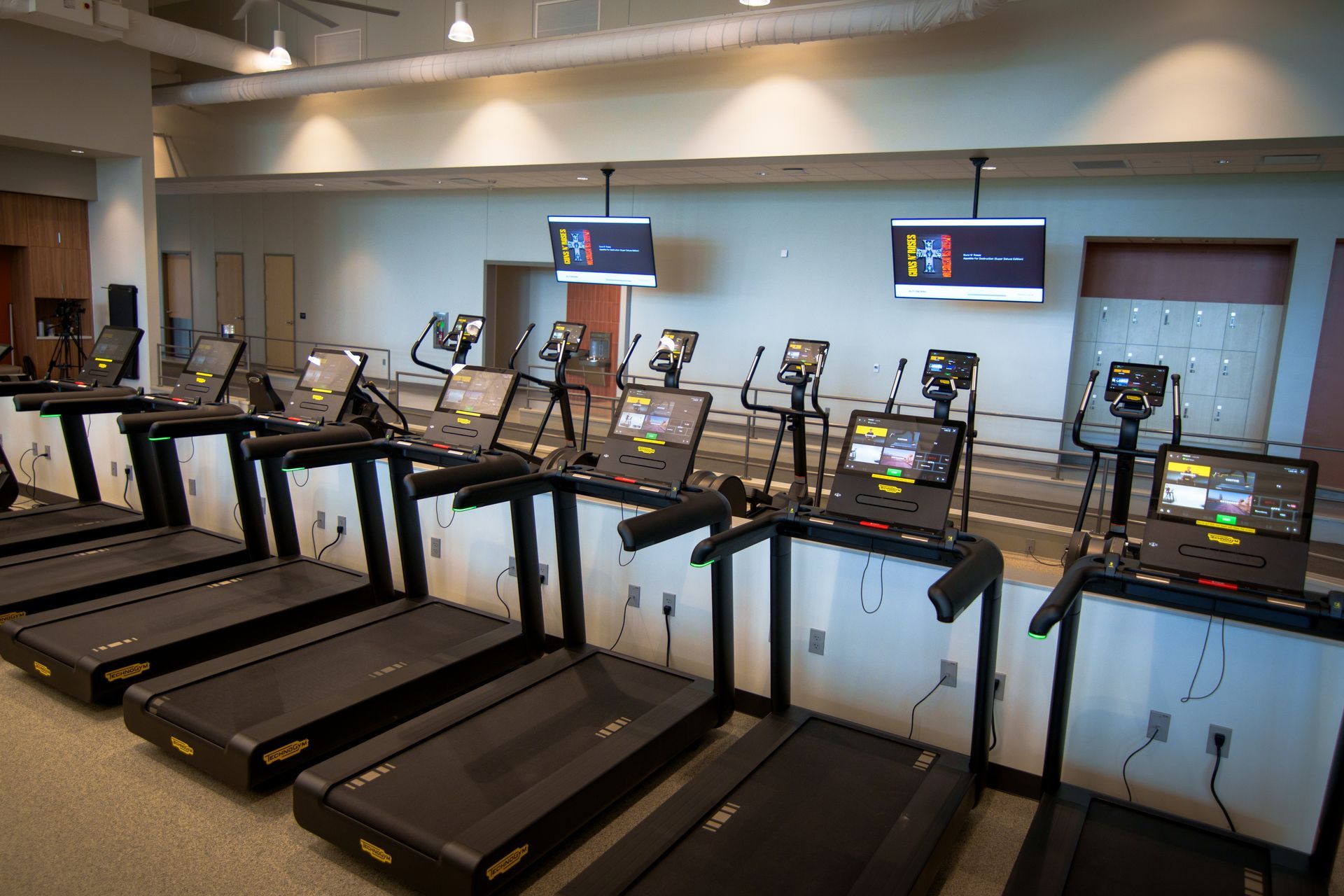 A row of treadmills are lined up in a gym.