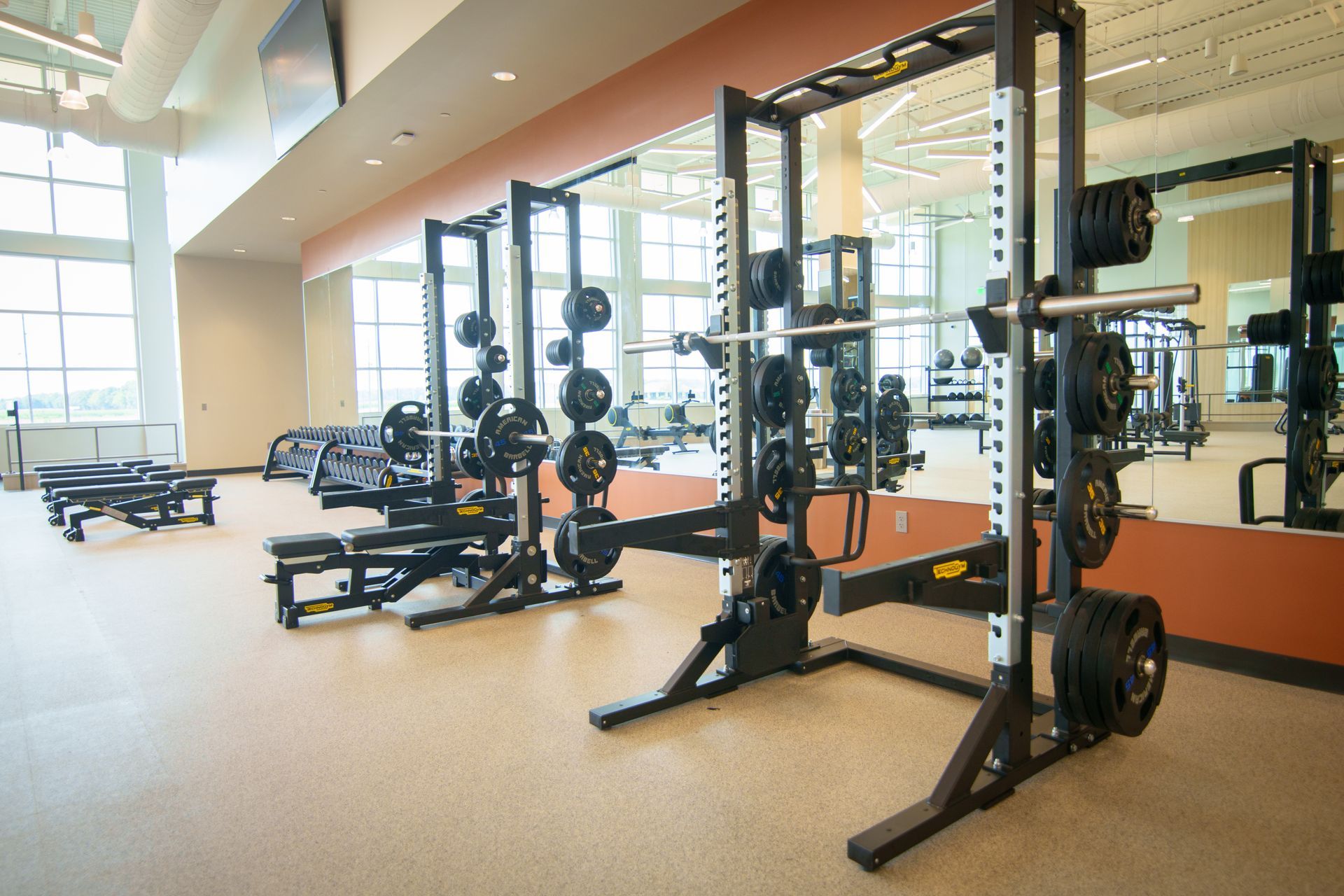 A gym with a lot of exercise equipment and a large mirror.