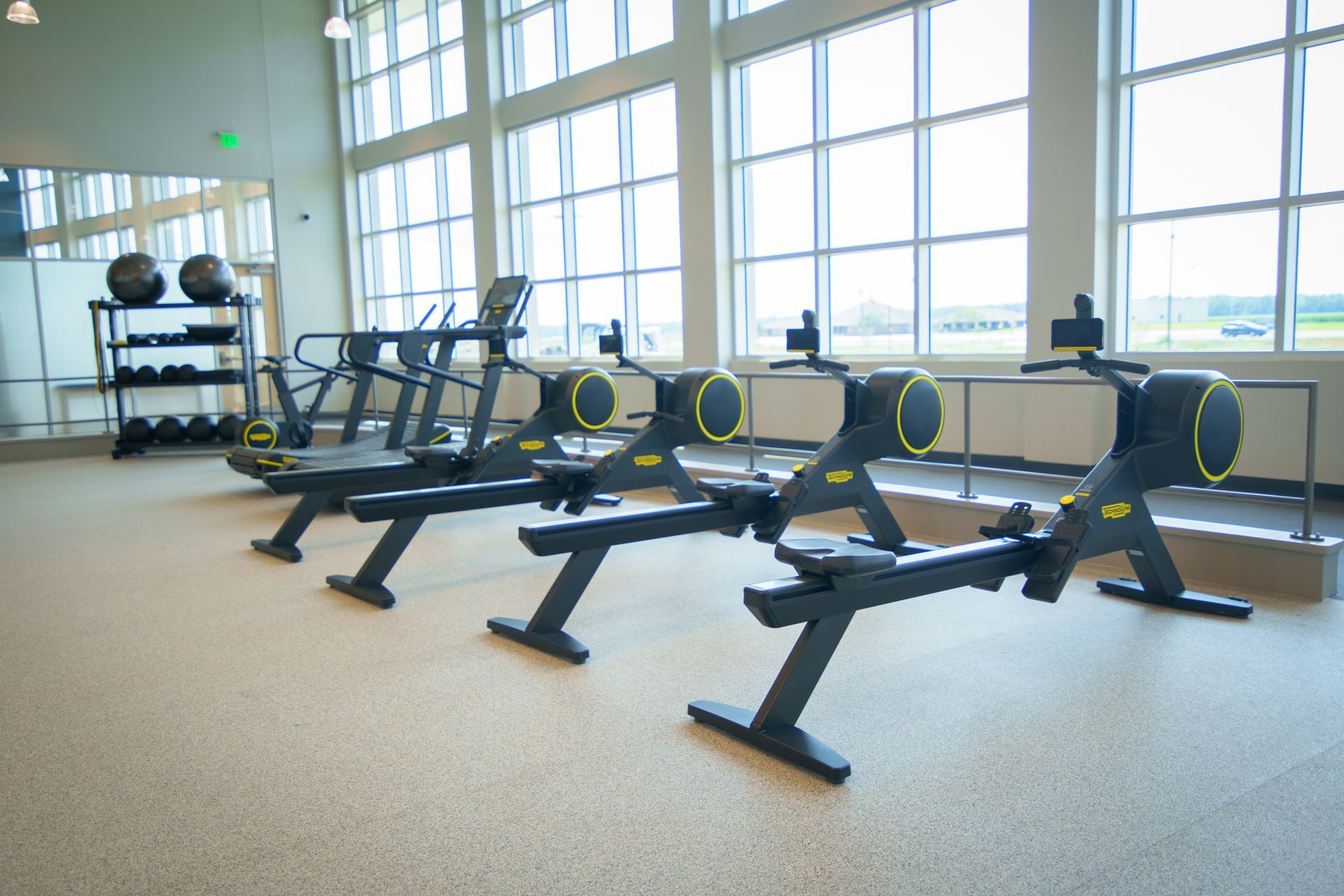 A row of rowing machines are lined up in a gym.