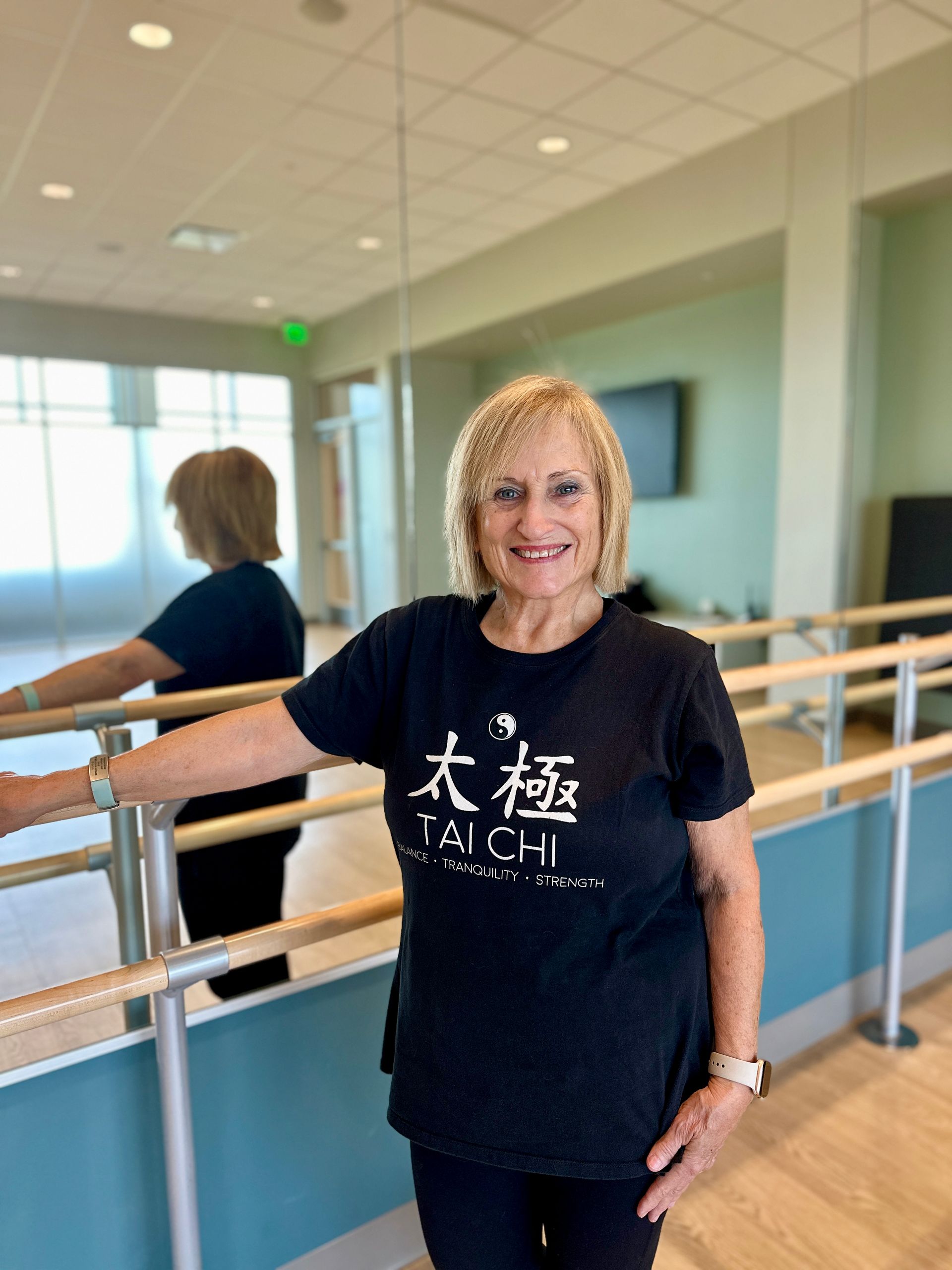 A woman is standing in front of a mirror in a dance studio.