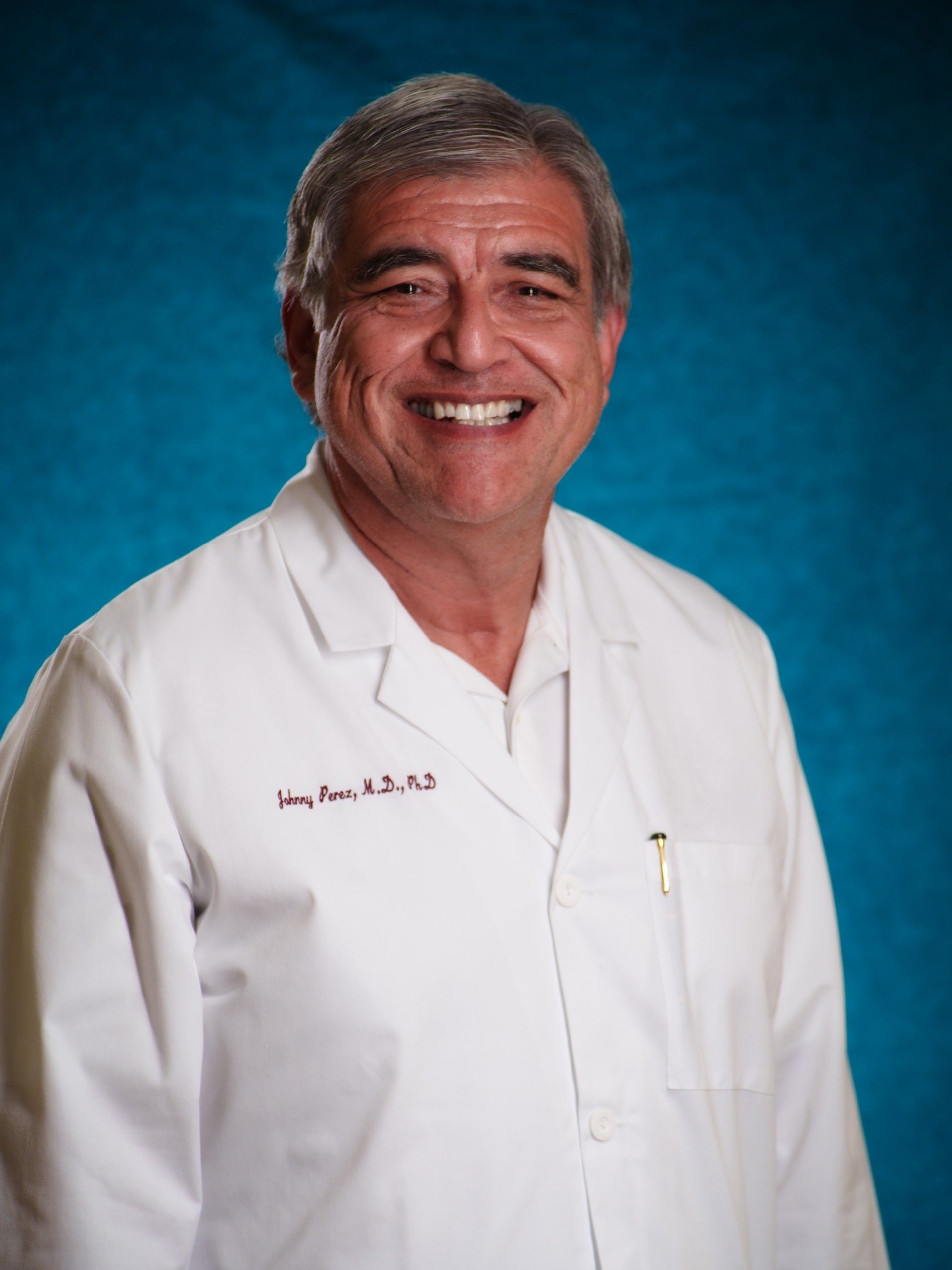 A man in a white lab coat is smiling for the camera