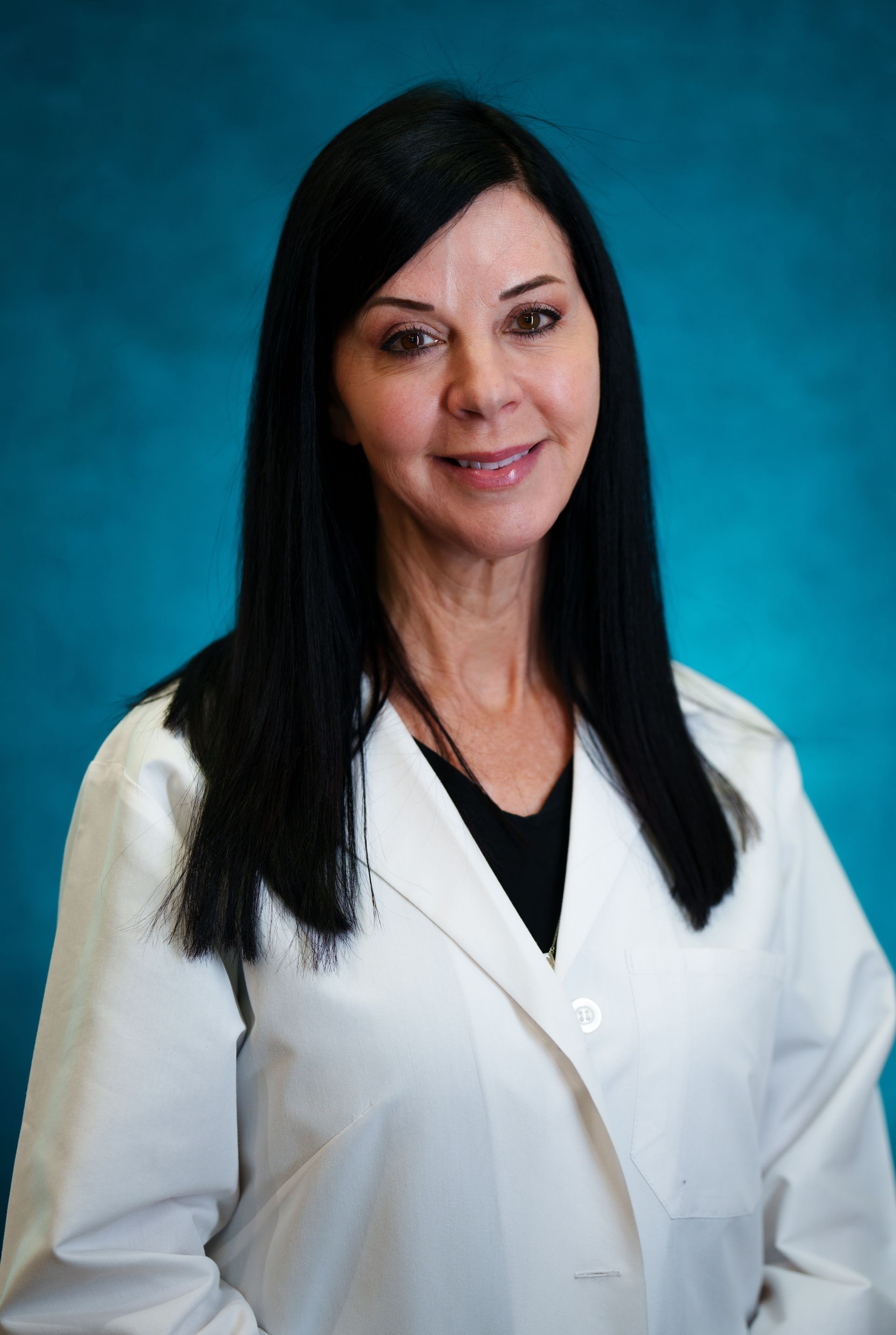 A woman in a white lab coat is smiling for the camera