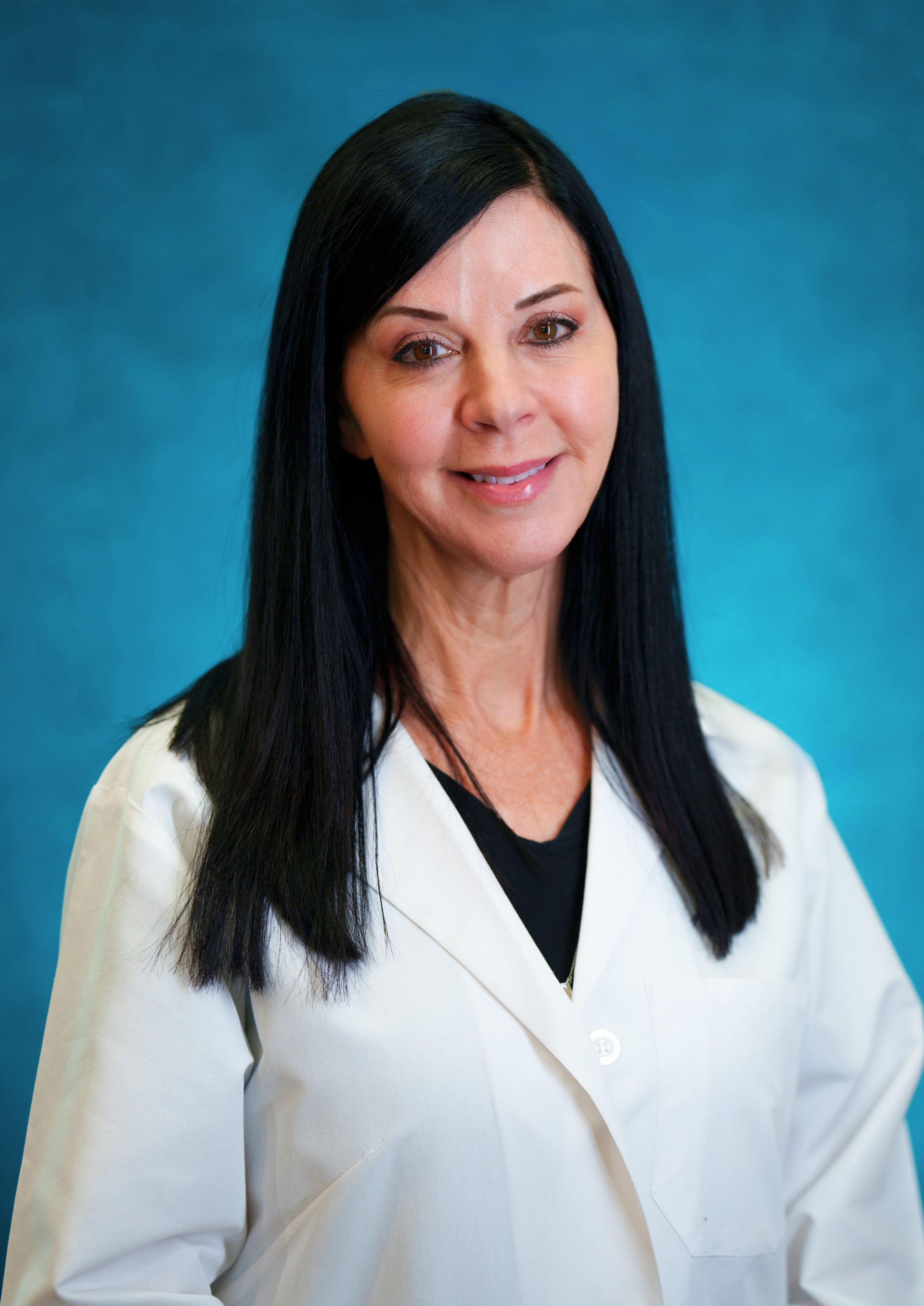 A woman in a white lab coat is smiling for the camera
