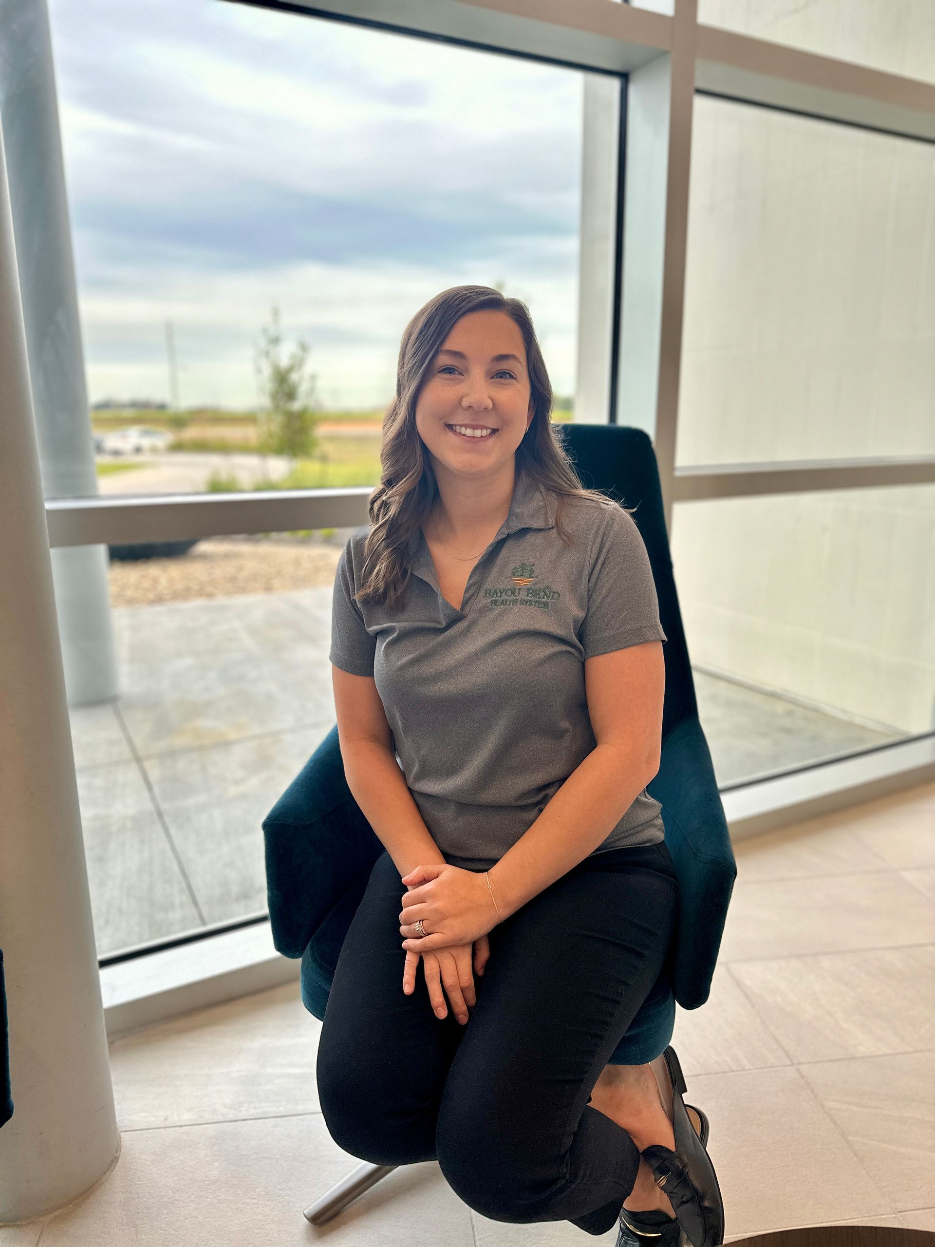 A woman is sitting in a chair in front of a window.