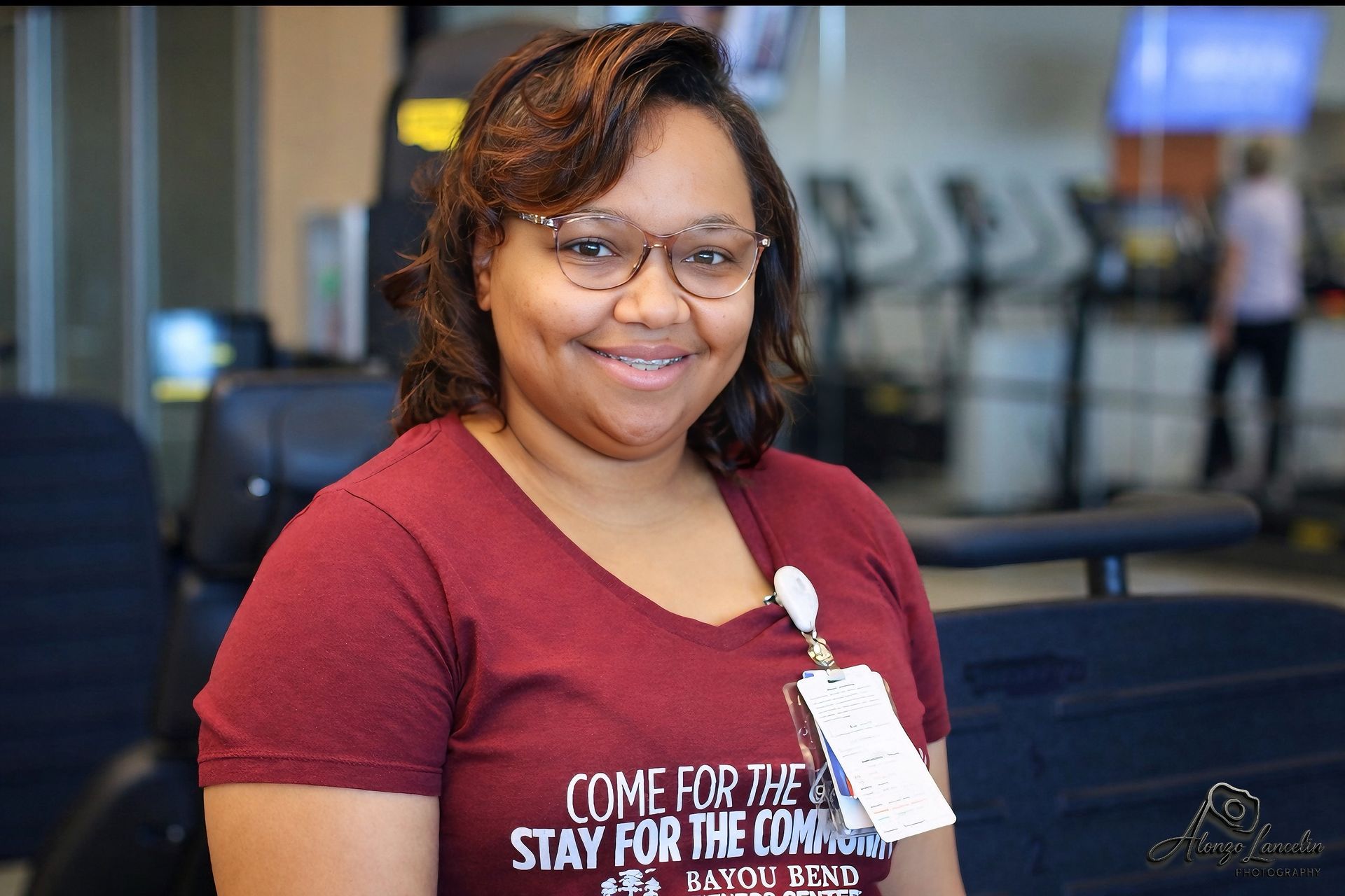 A woman is sitting on a treadmill in a gym.