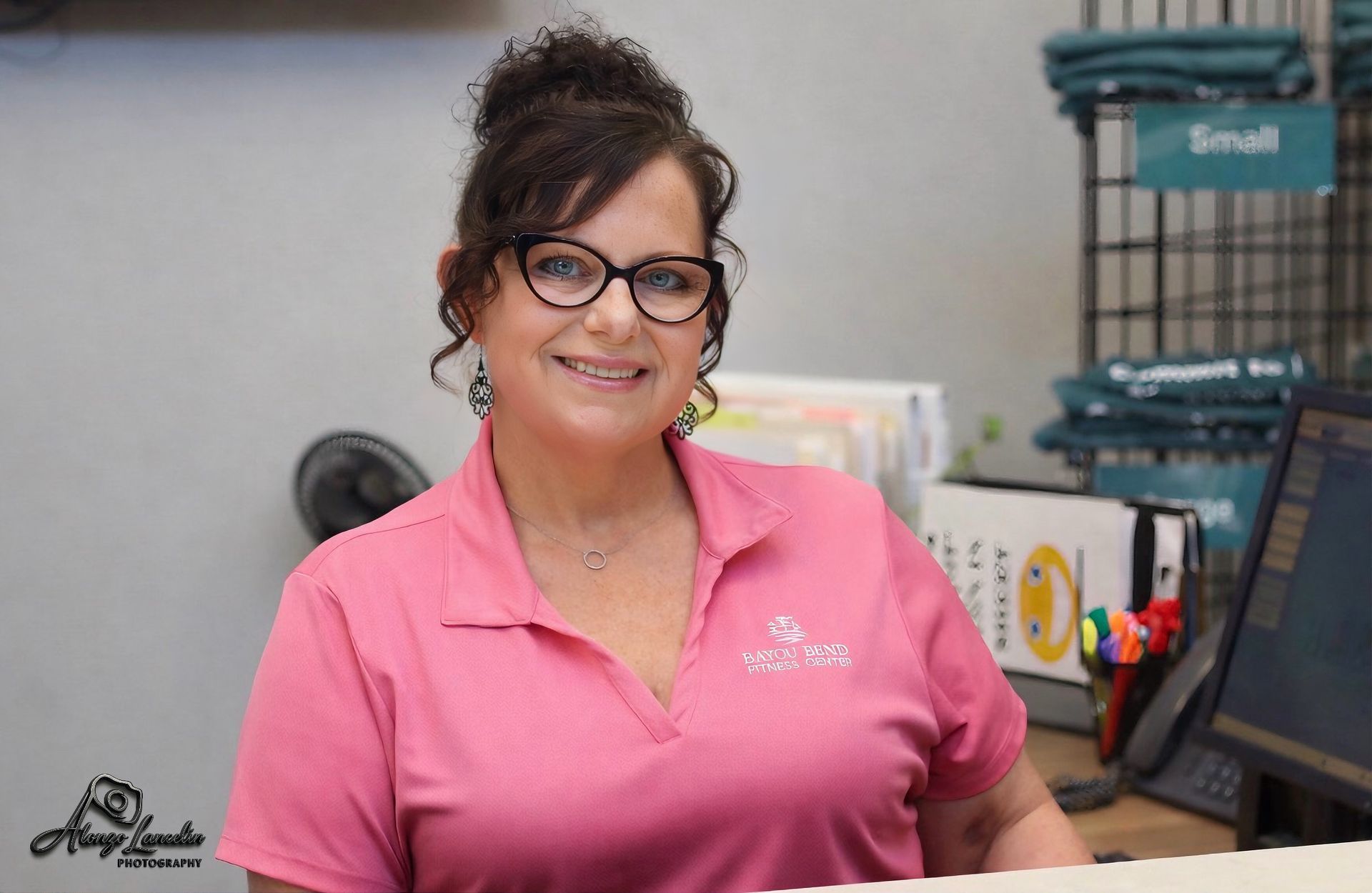 A woman is sitting at a counter in front of a bayou bend fitness center sign.
