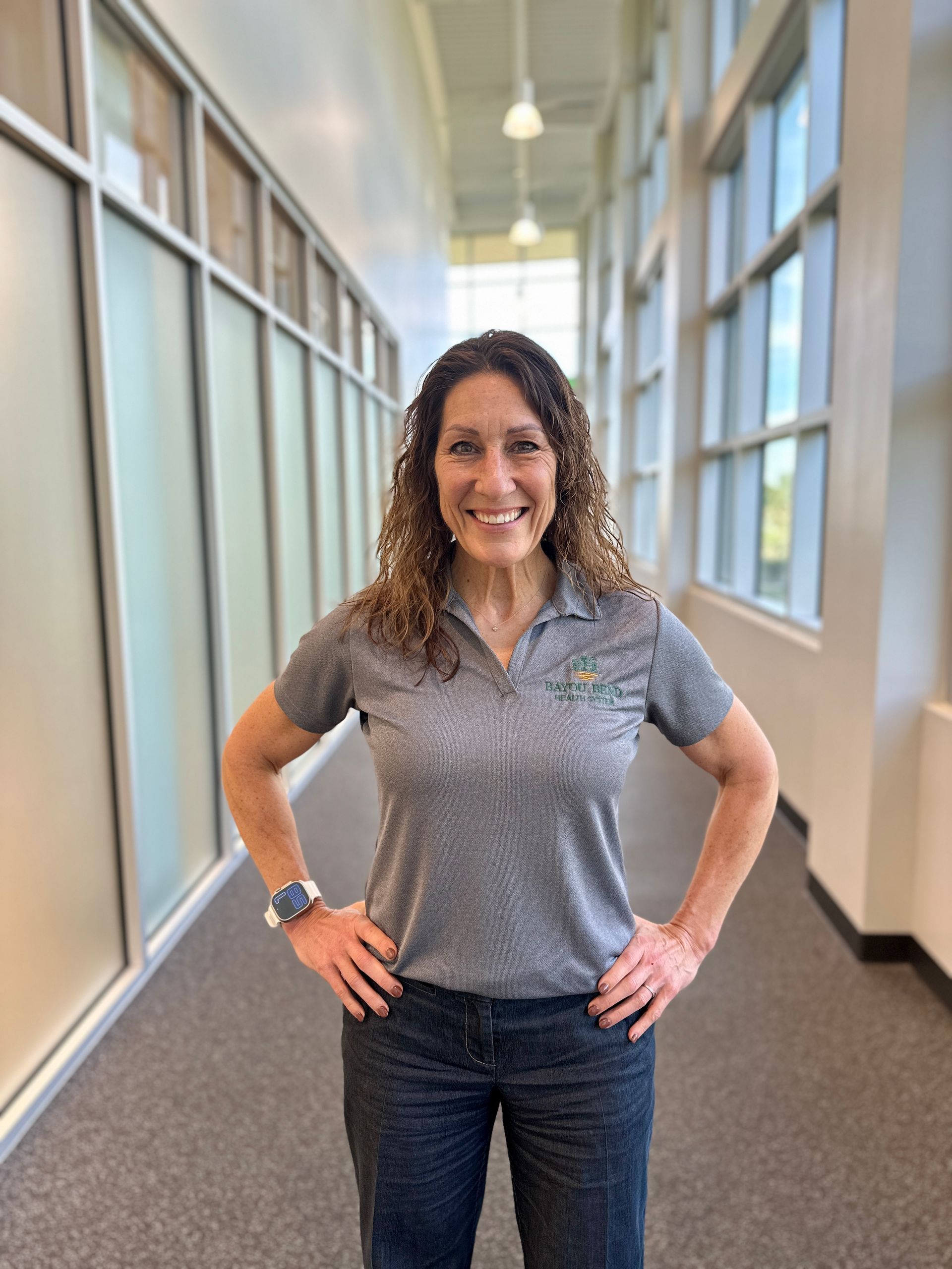 A woman is standing in a hallway with her hands on her hips.