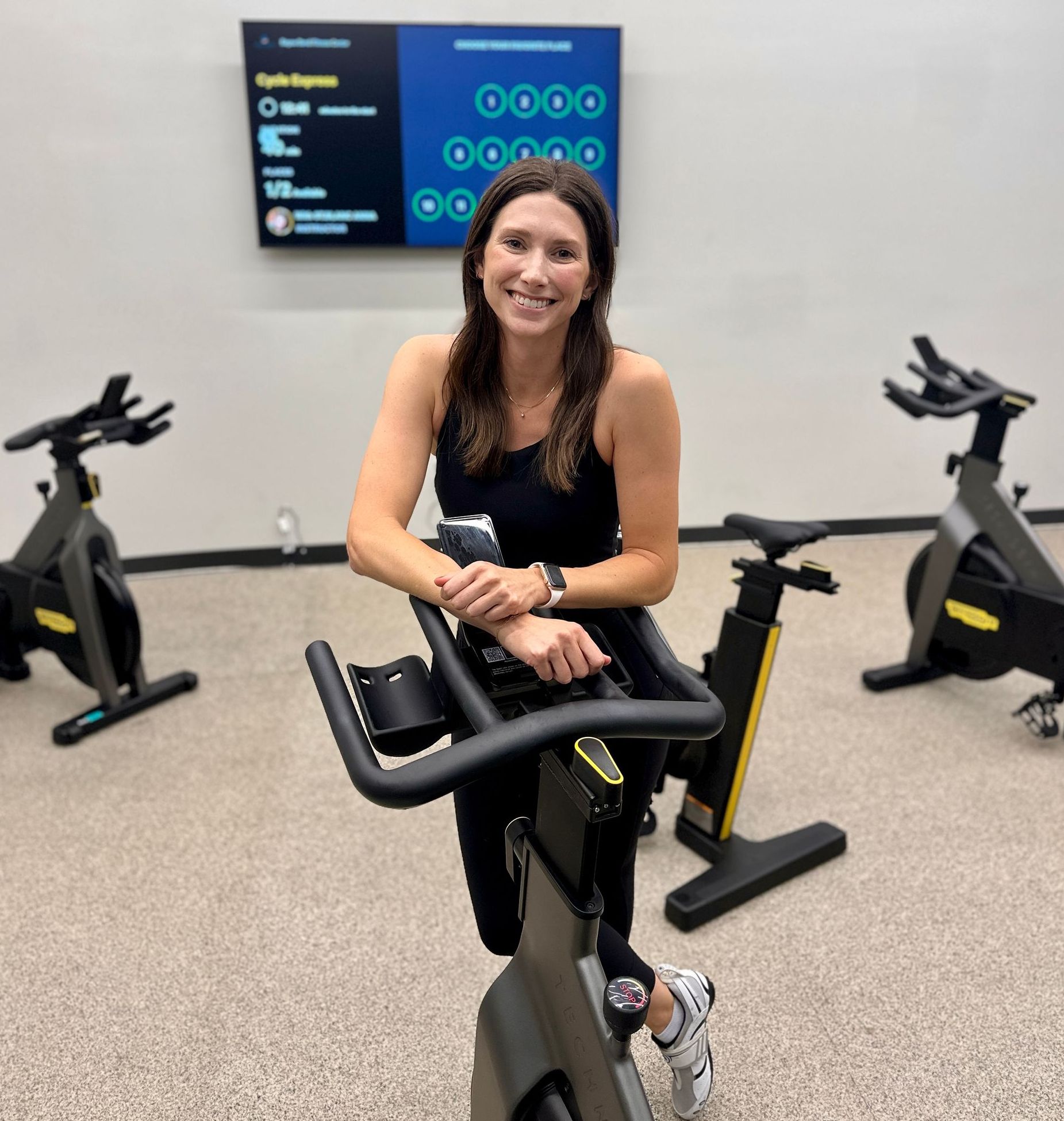 A woman is riding an exercise bike in a gym