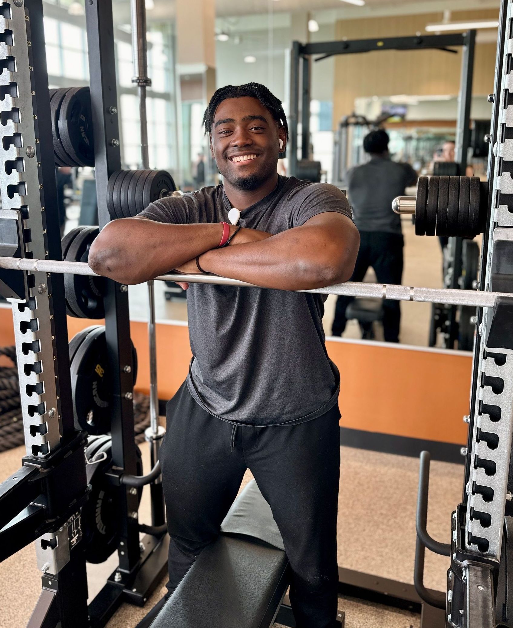 A man is leaning on a barbell in a gym.