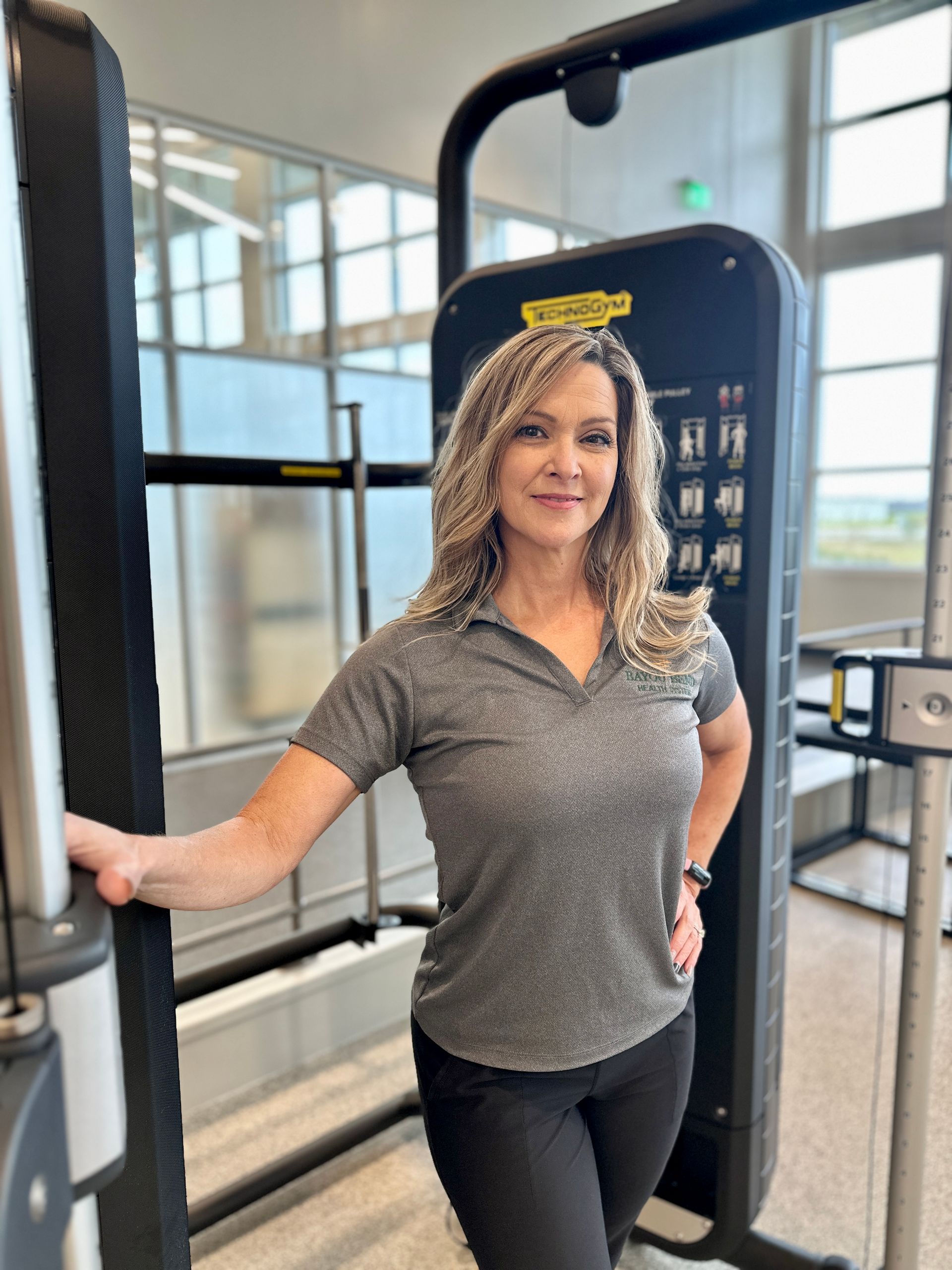 A woman is standing next to a machine in a gym.