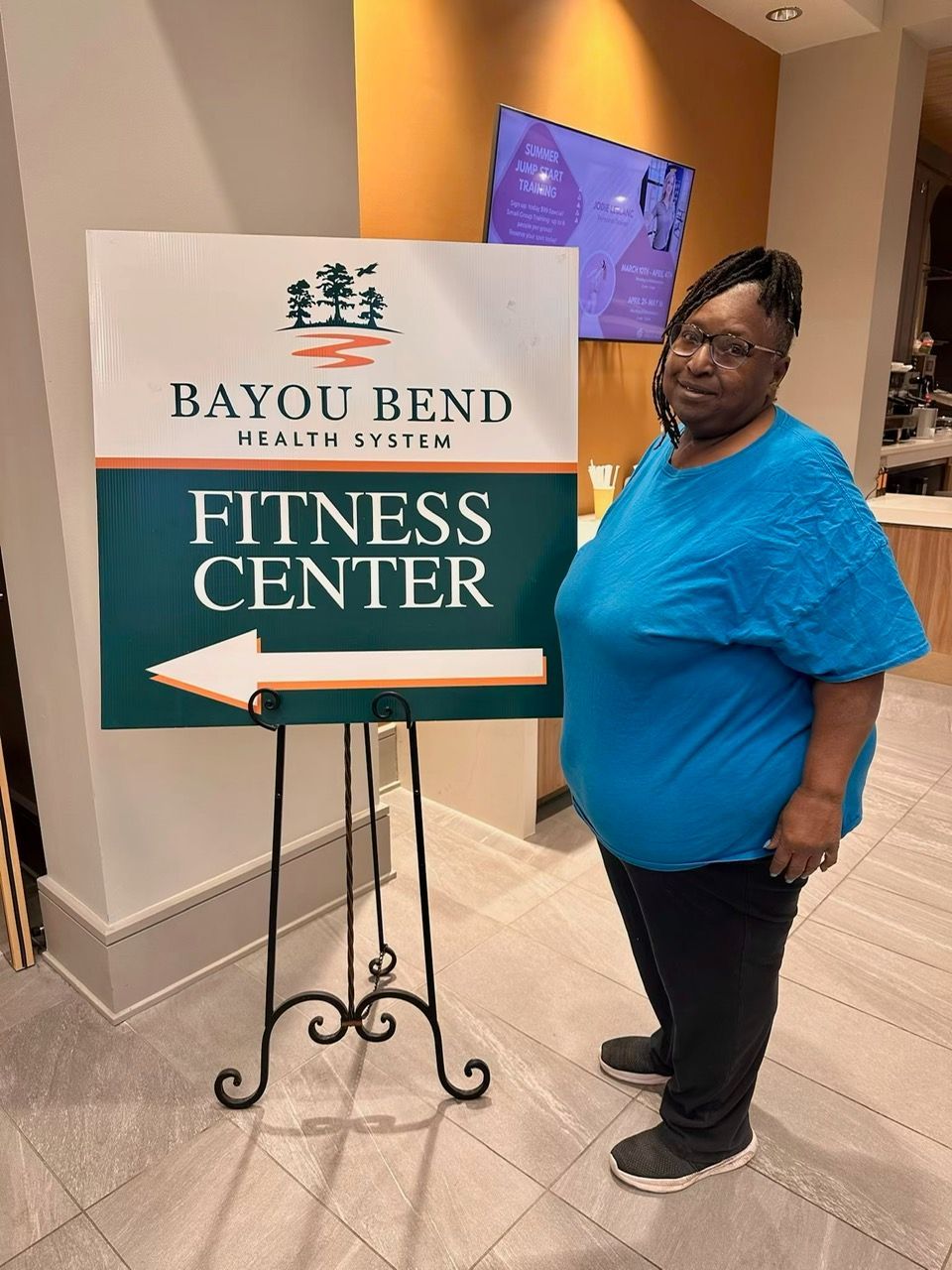 A woman is standing in front of a sign that says bayou bend fitness center
