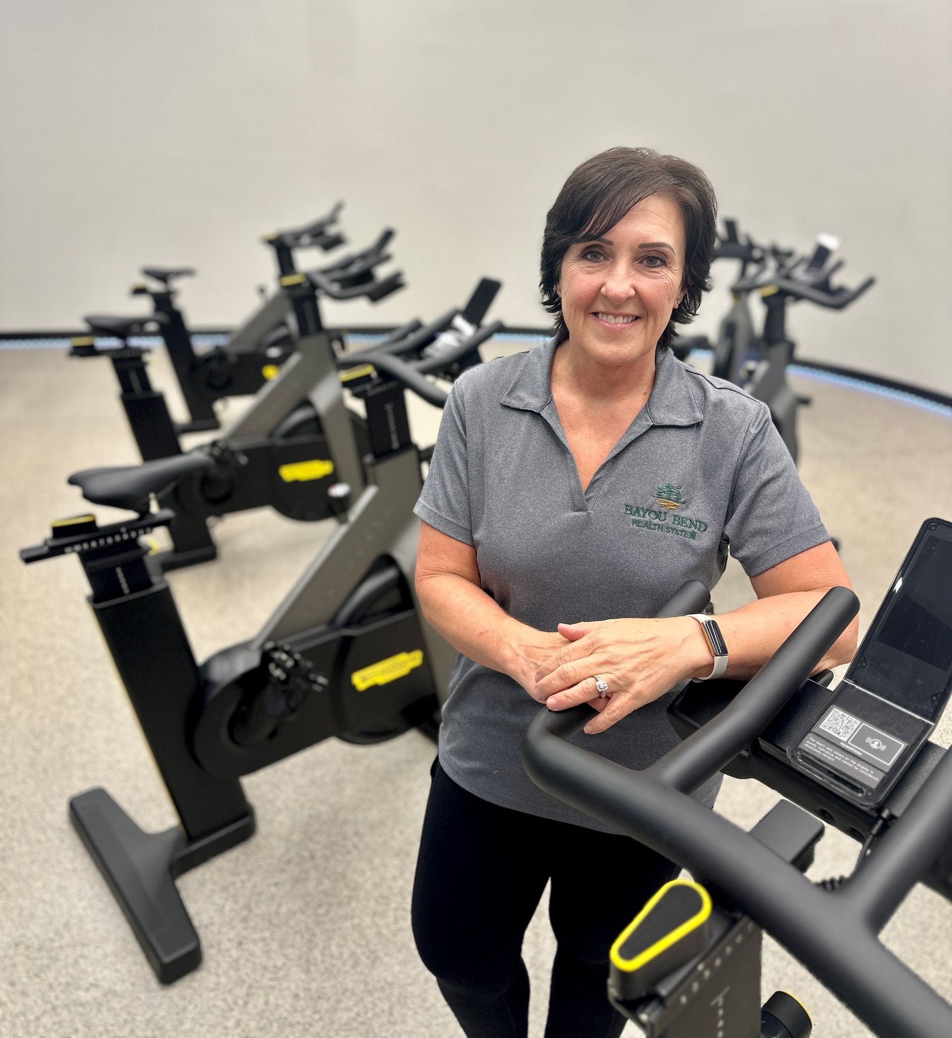 A woman is standing next to an exercise bike in a gym