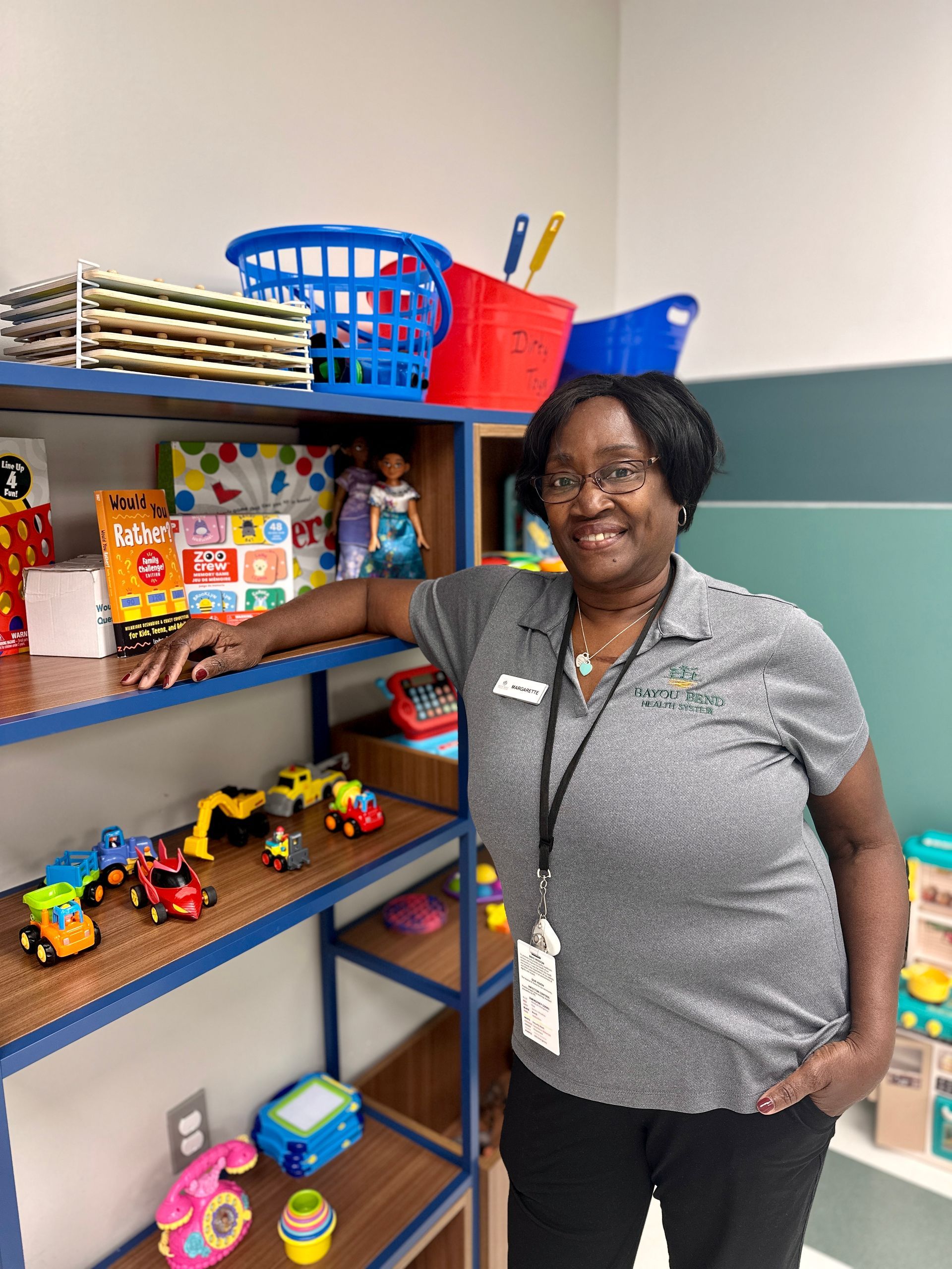 A woman is standing in front of a shelf full of toys.