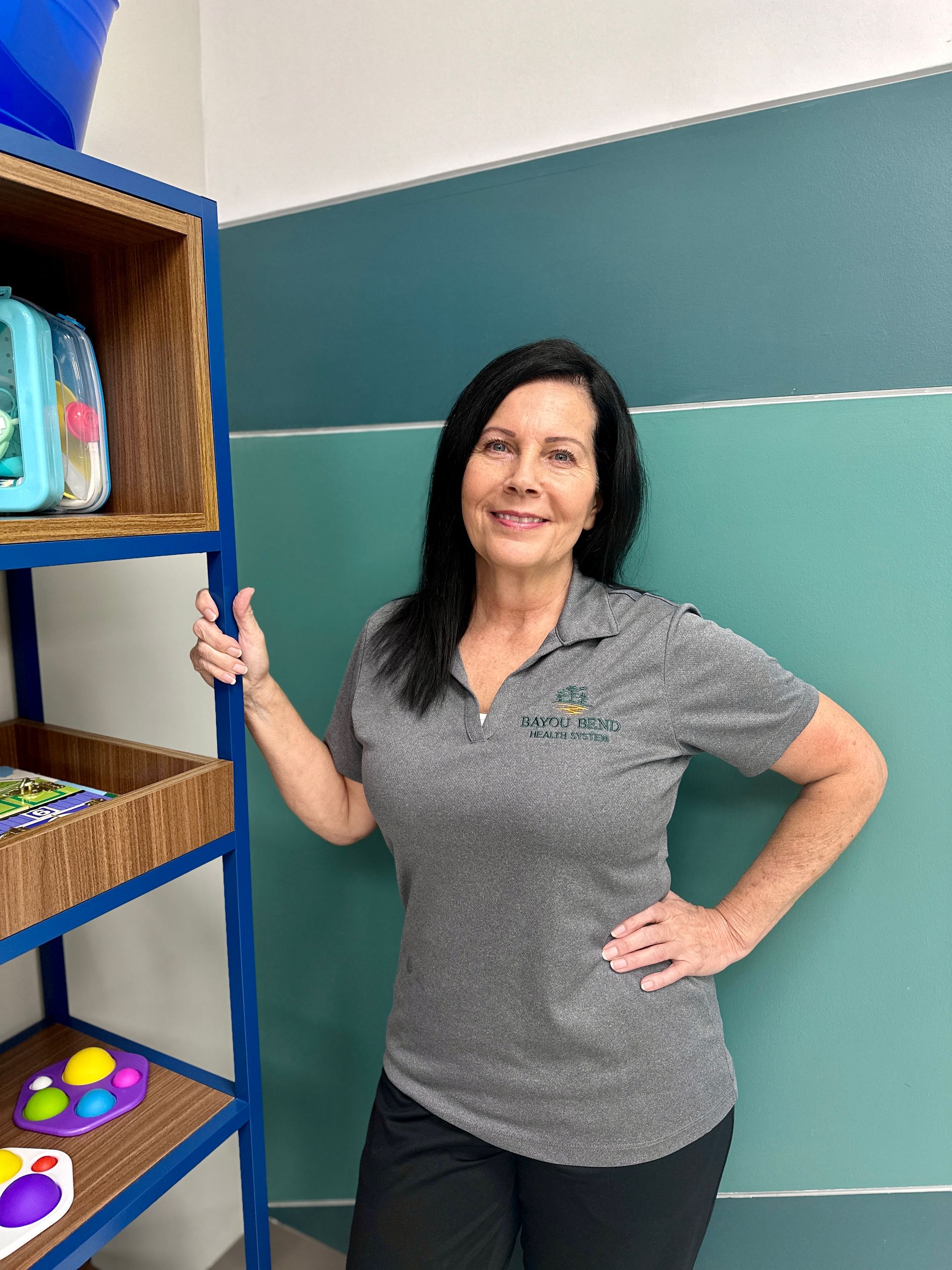 A woman is standing in front of a shelf with toys on it.
