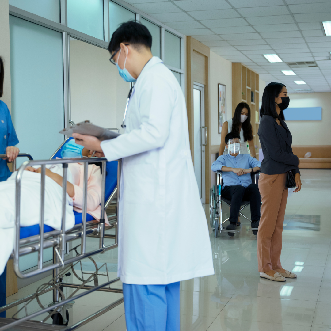A doctor wearing a mask is talking to a patient in a wheelchair