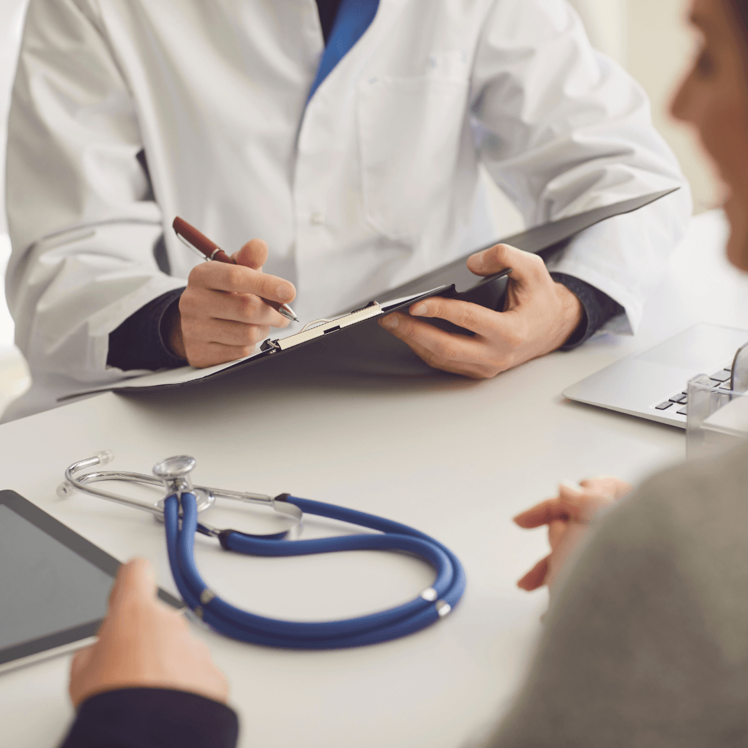 A doctor is talking to a patient while holding a clipboard and a stethoscope.