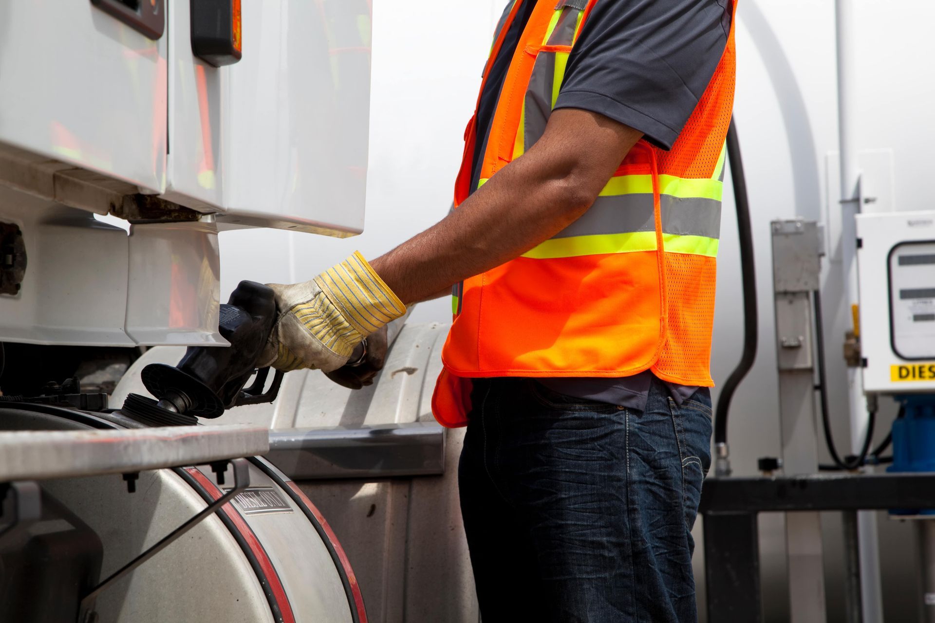Person in safety vest operating equipment on a white truck.