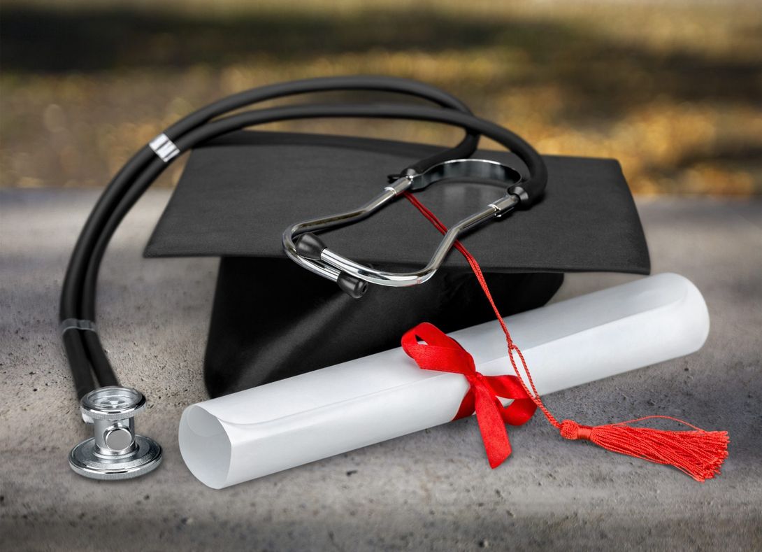 Tocco accademico con stetoscopio e diploma di laurea
